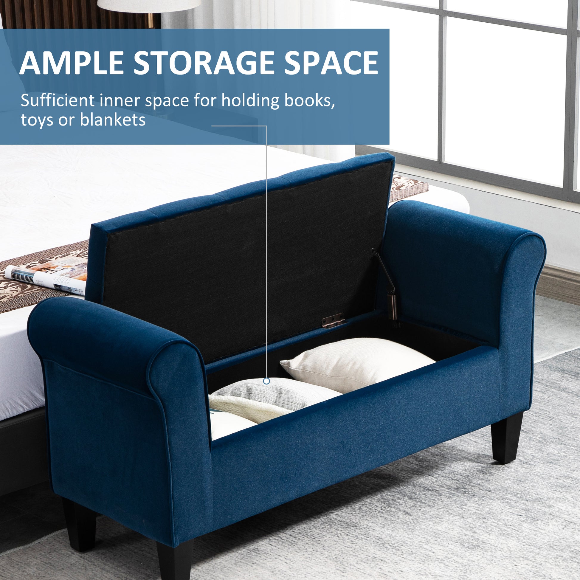 Open navy blue upholstered storage bench with rolled arms showing stored pillows and blankets