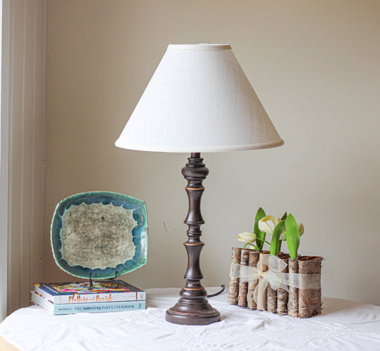 Dark wood table lamp with cream linen shade and decorative base