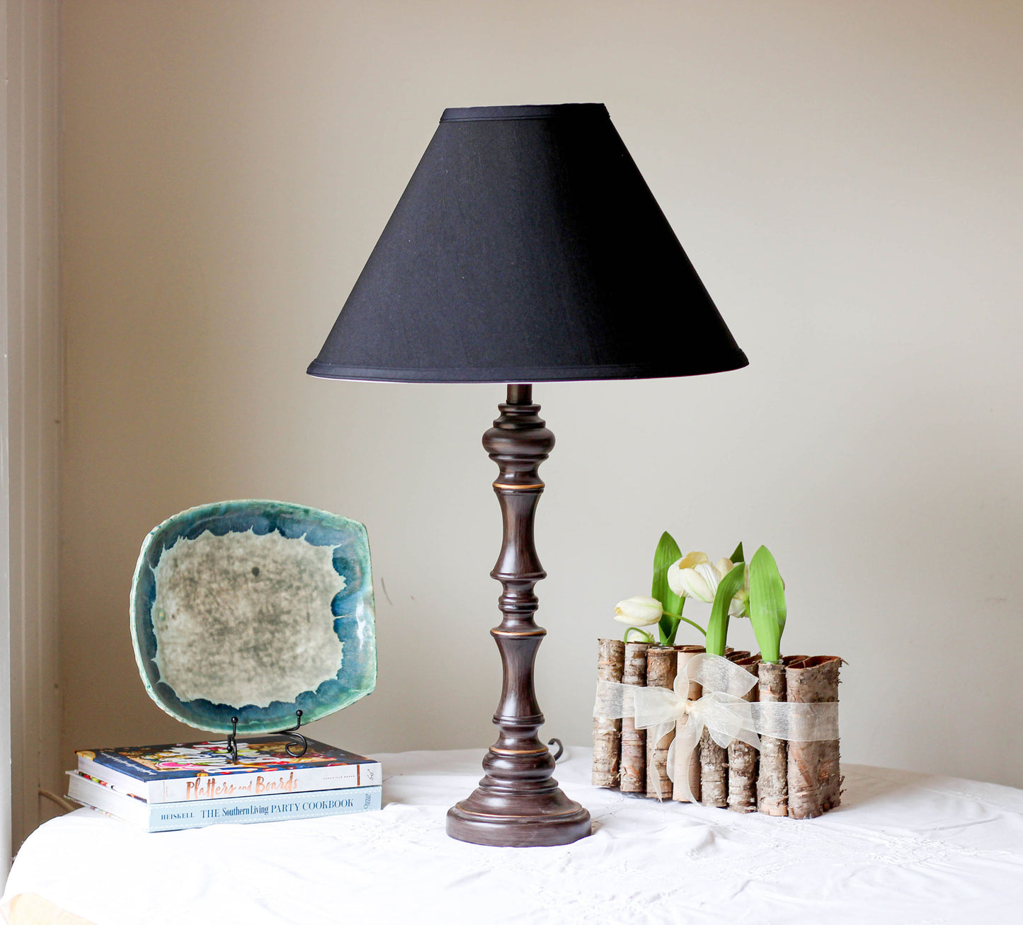 Dark bronze table lamp with black lampshade and decorative base on white tablecloth