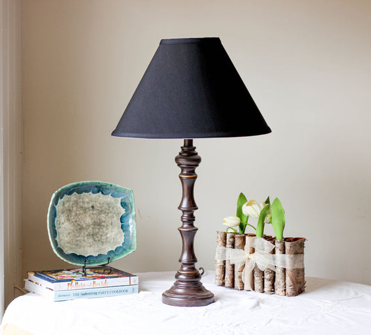 Dark bronze table lamp with black lampshade and decorative base on white tablecloth