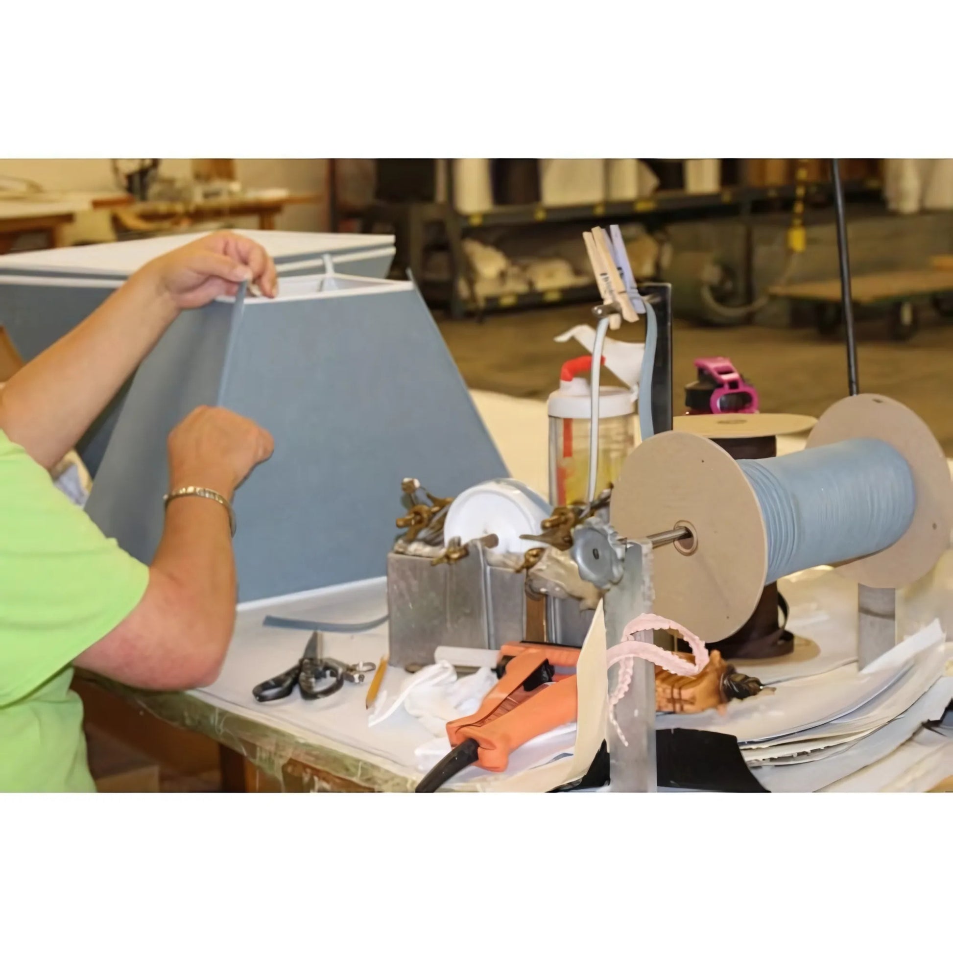 Gray fabric lampshade assembly with spools of trim and hot glue gun