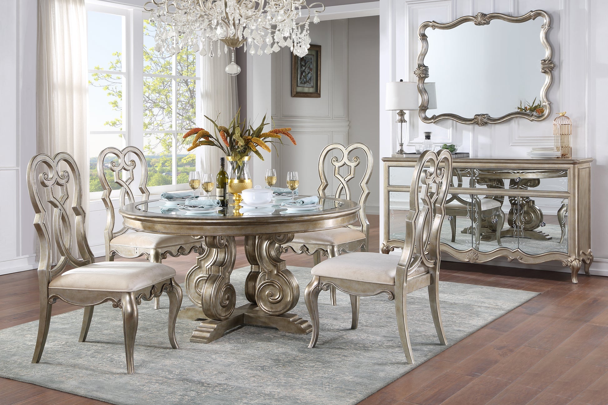 Silver ornate dining table with glass top and four upholstered chairs set for dinner