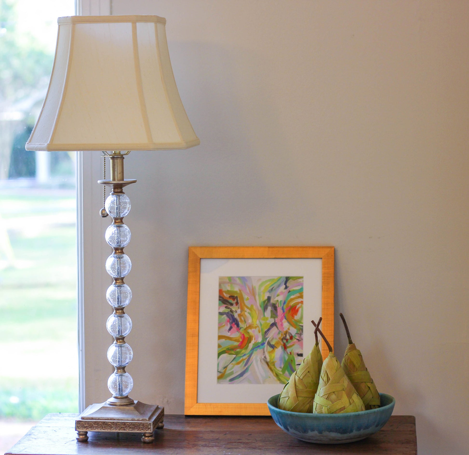 A tall classic table lamp with a cream shade and a clear bubbleeffect glass column base