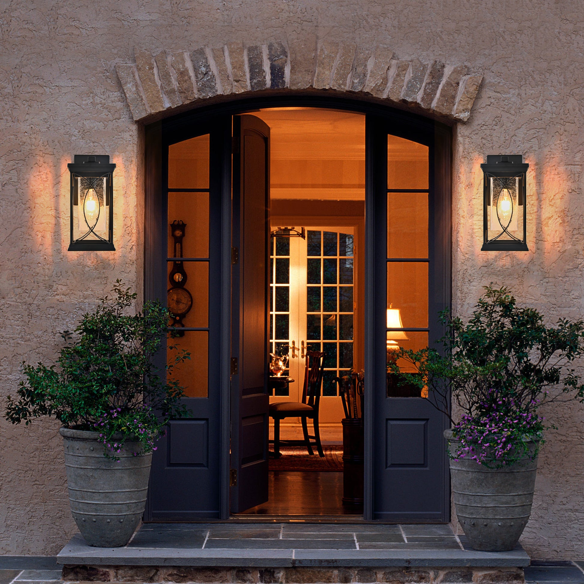 Black outdoor lantern with seeded glass and ornate scrollwork detail provides ambient lighting