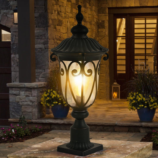 Black ornate traditional post lantern with glass shade and warm glow