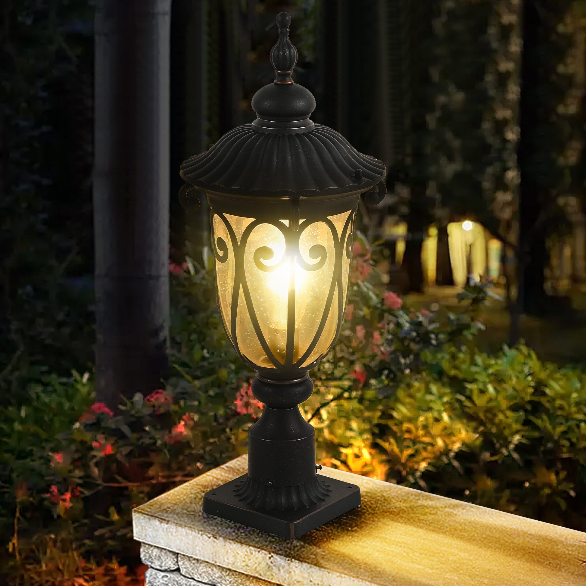 Black ornate post lantern with amber seeded glass shade illuminated outdoors