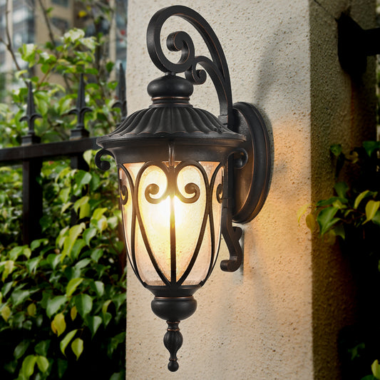 Ornate black outdoor wall lamp with seeded glass and scroll details providing warm porch lighting