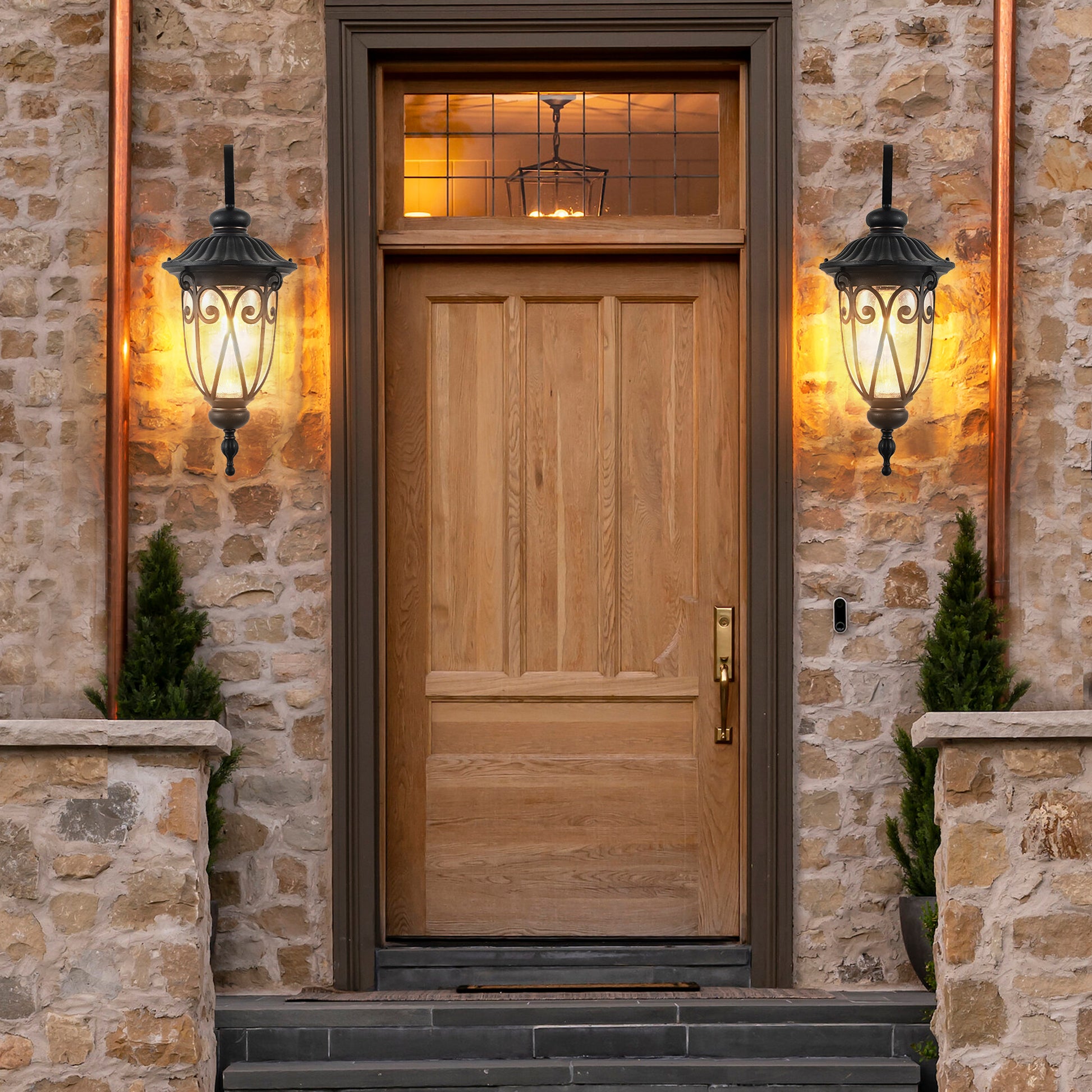 Black ornate outdoor wall lantern with clear seeded glass providing warm exterior lighting