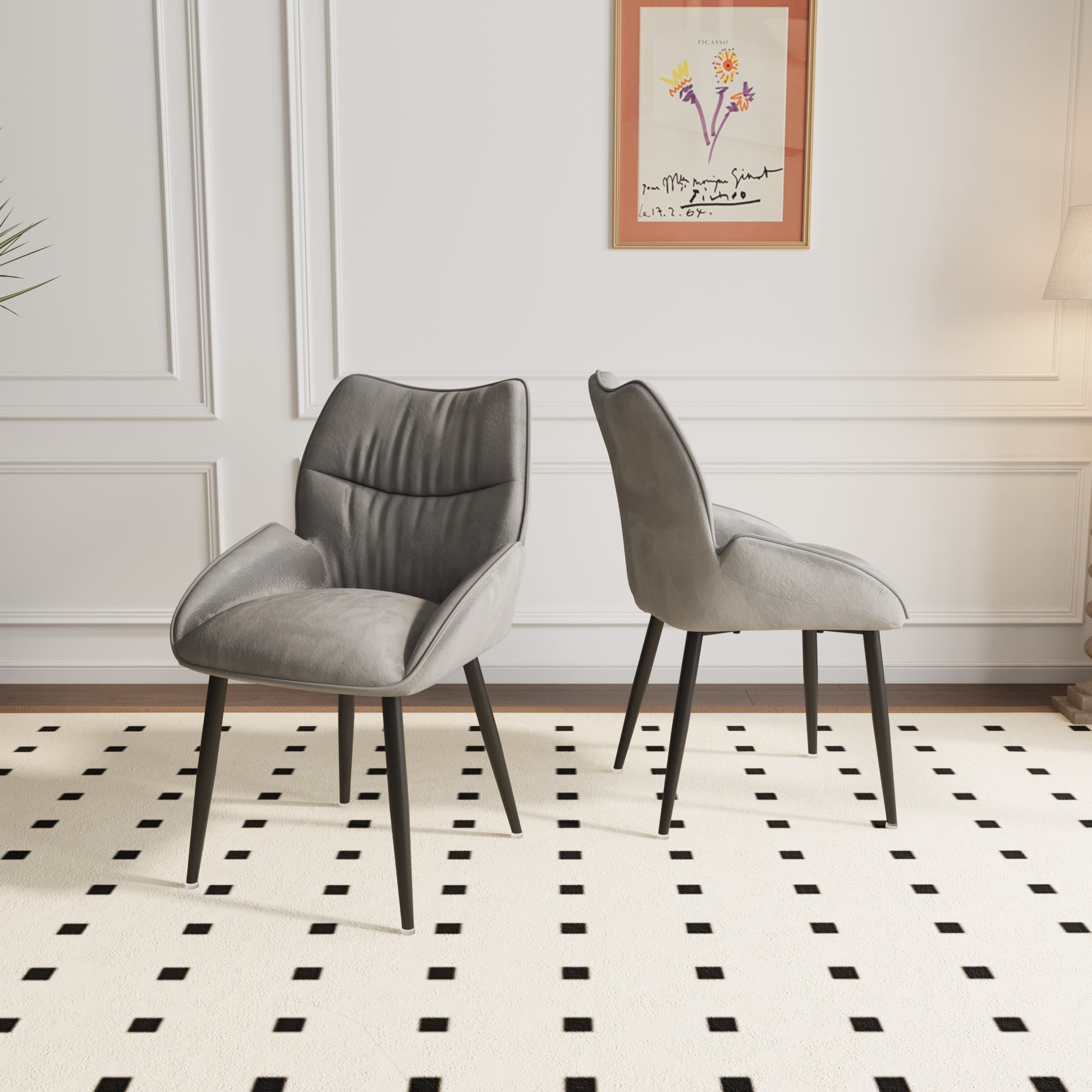 Two grey upholstered dining chairs with black metal legs on a patterned rug
