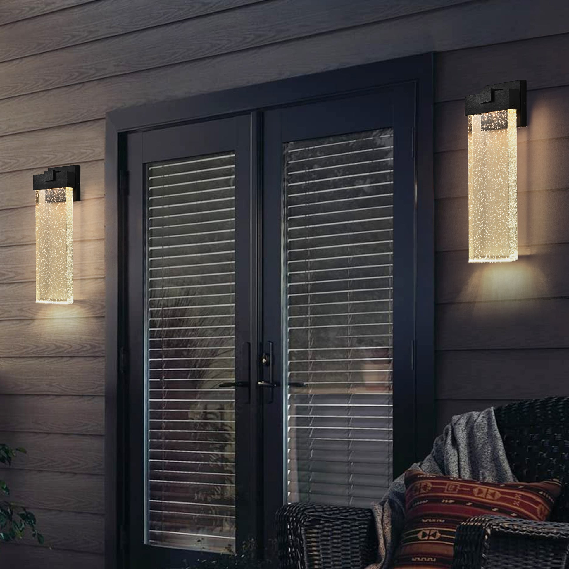 Modern outdoor wall light with clear seeded glass and black metal frame providing ambient lighting