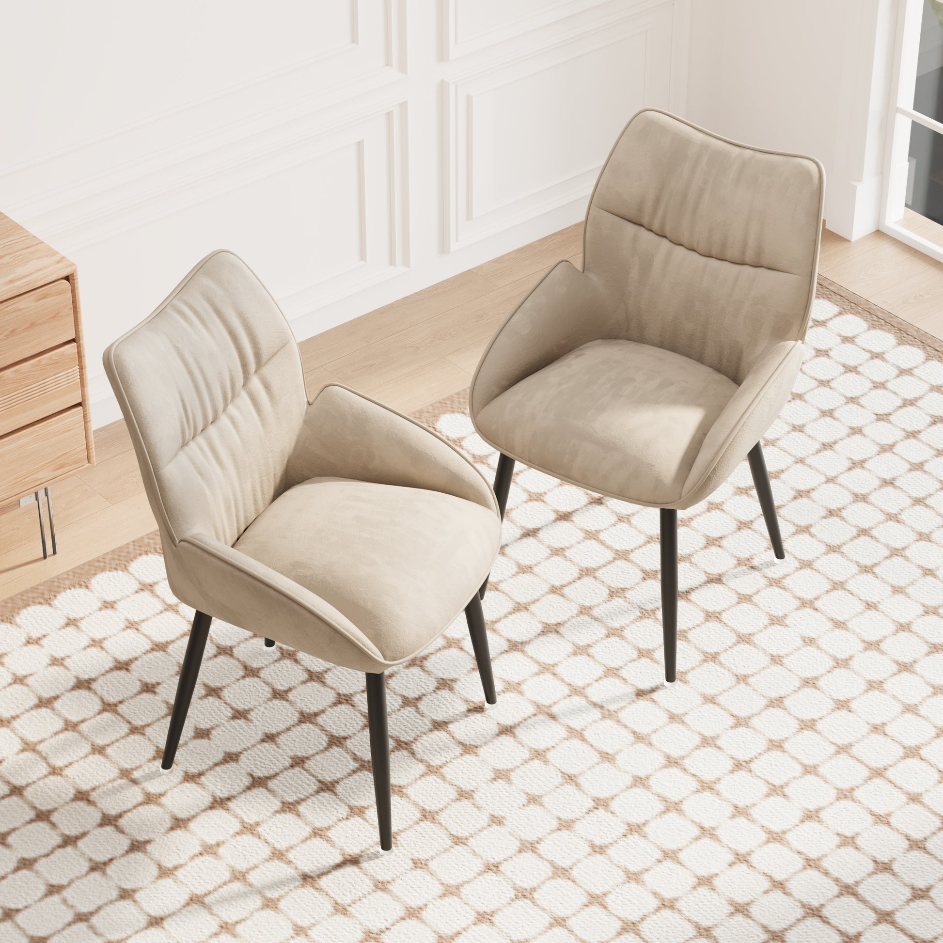 Two beige upholstered accent chairs with black legs on a cream and tan geometric rug