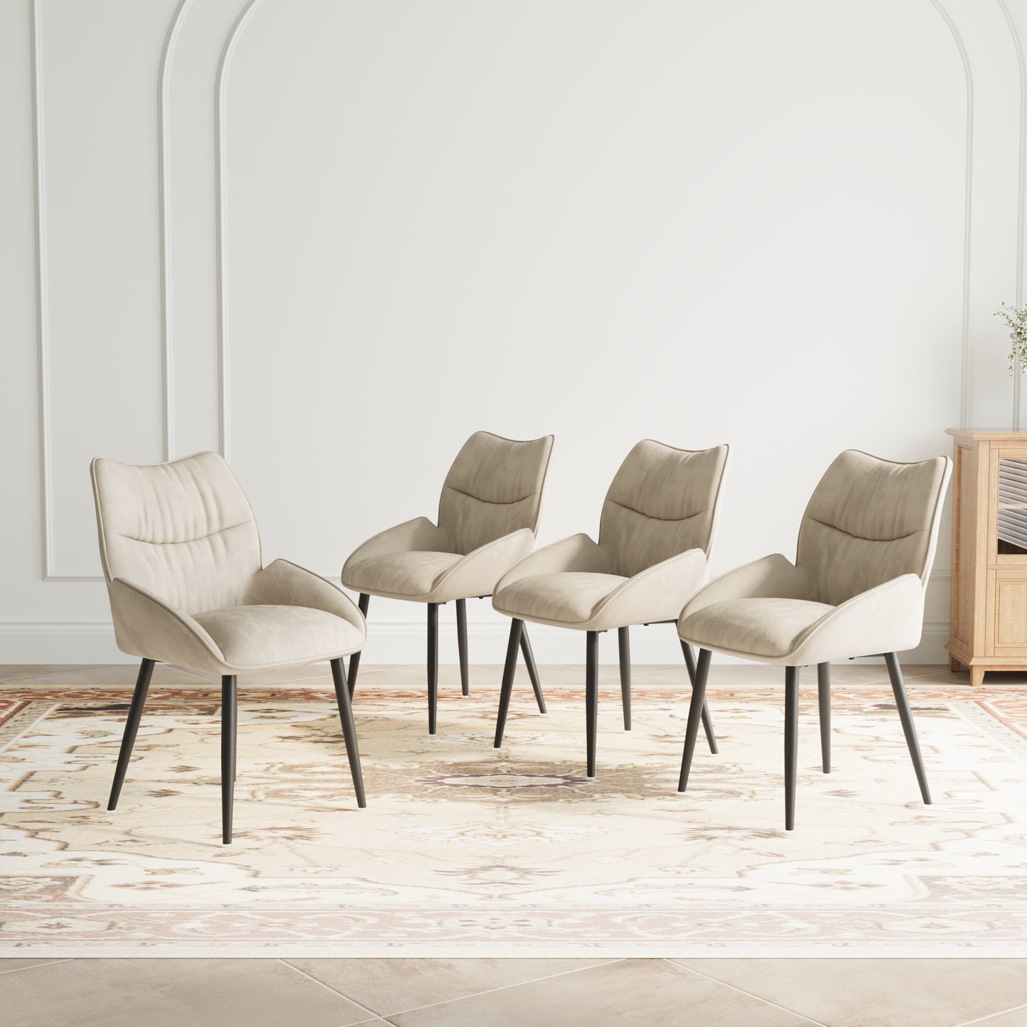 Four beige upholstered dining chairs with dark metal legs on an ornate rug