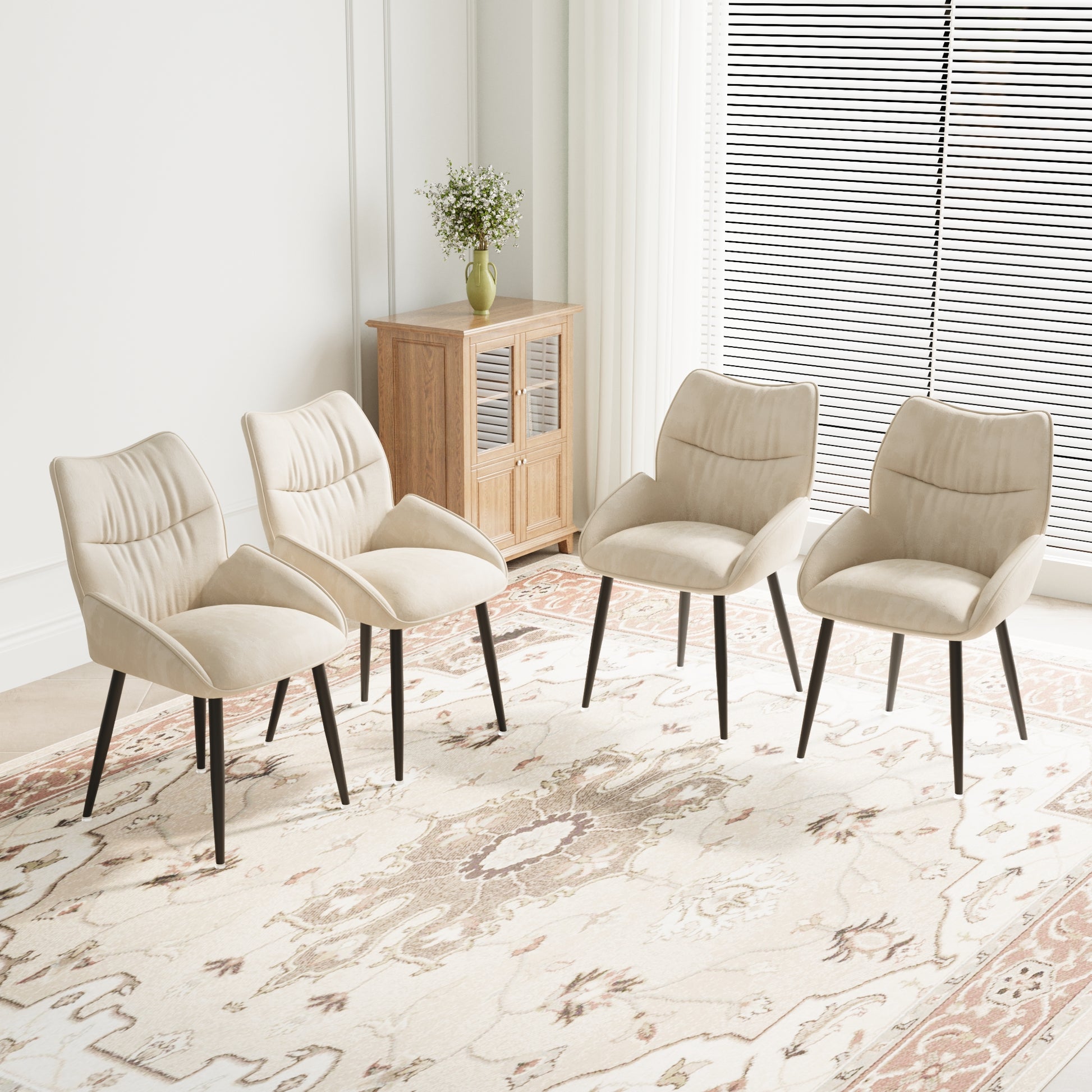 Four cream velvet dining chairs with dark tapered legs arranged on a patterned rug