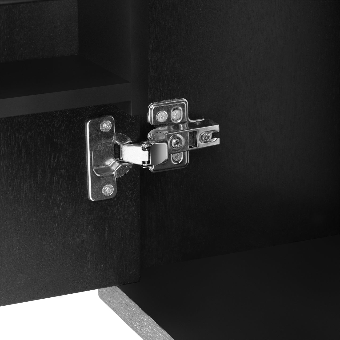 Closeup of a brushed nickel cabinet hinge on black wood grain door
