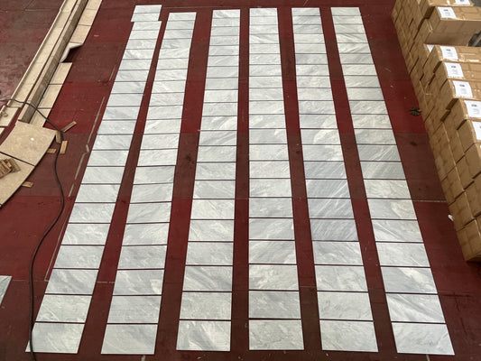 Light gray marble effect porcelain tiles laid out on a dark red floor