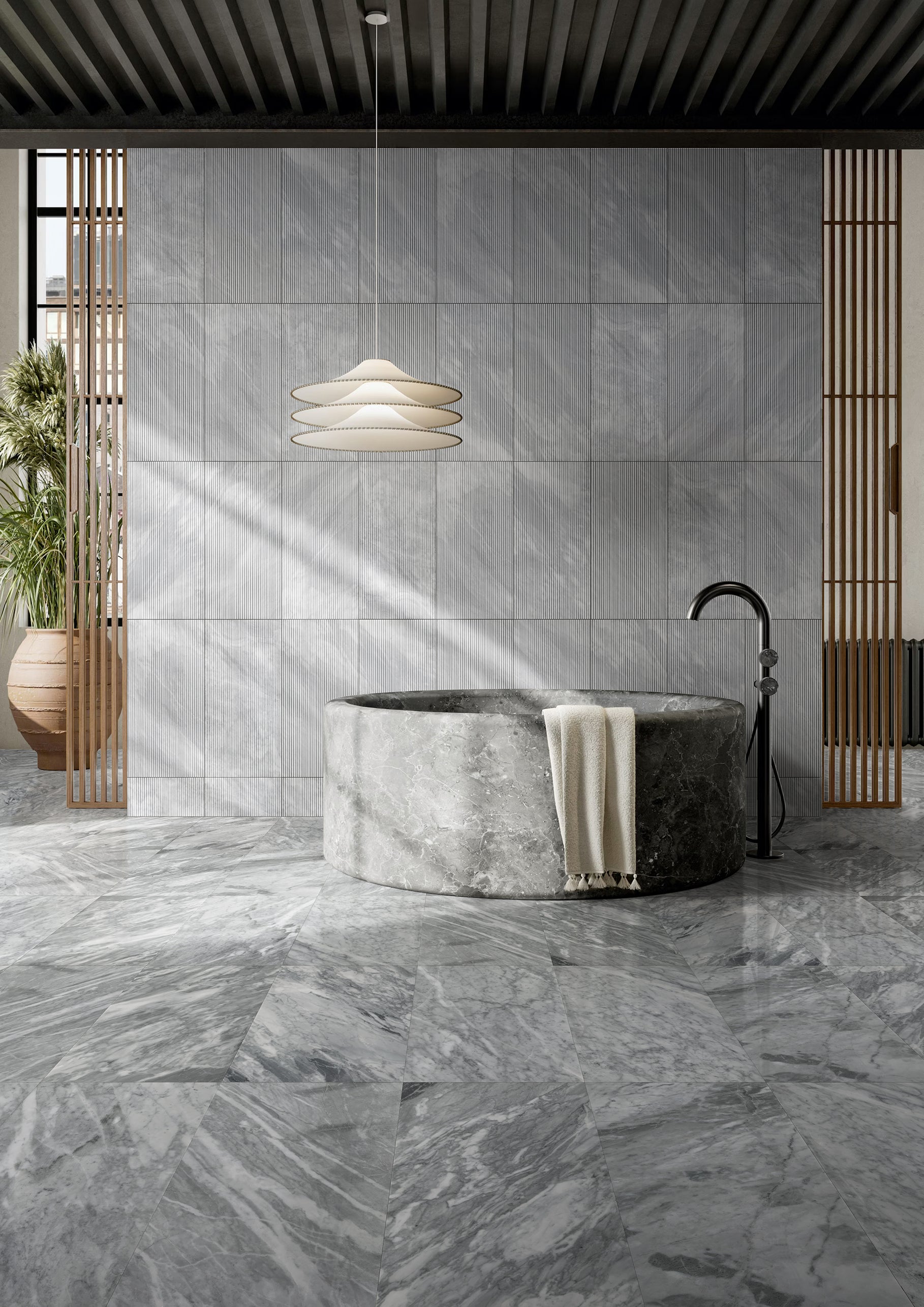 Modern freestanding marble bathtub with a sleek black faucet and white towel
