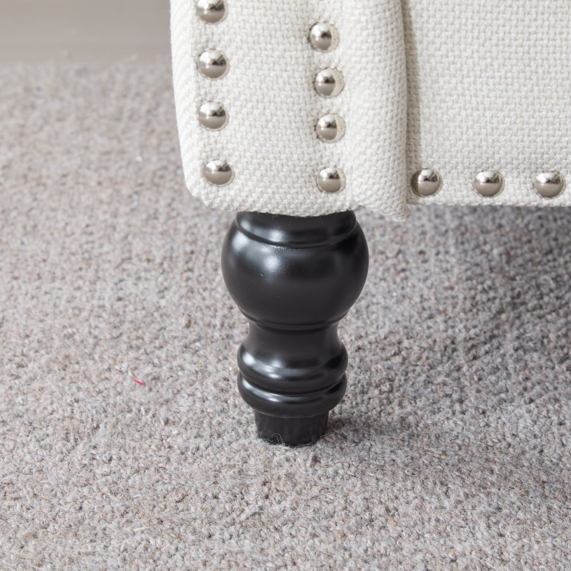 Cream linen accent chair with silver nailhead trim and black turned leg