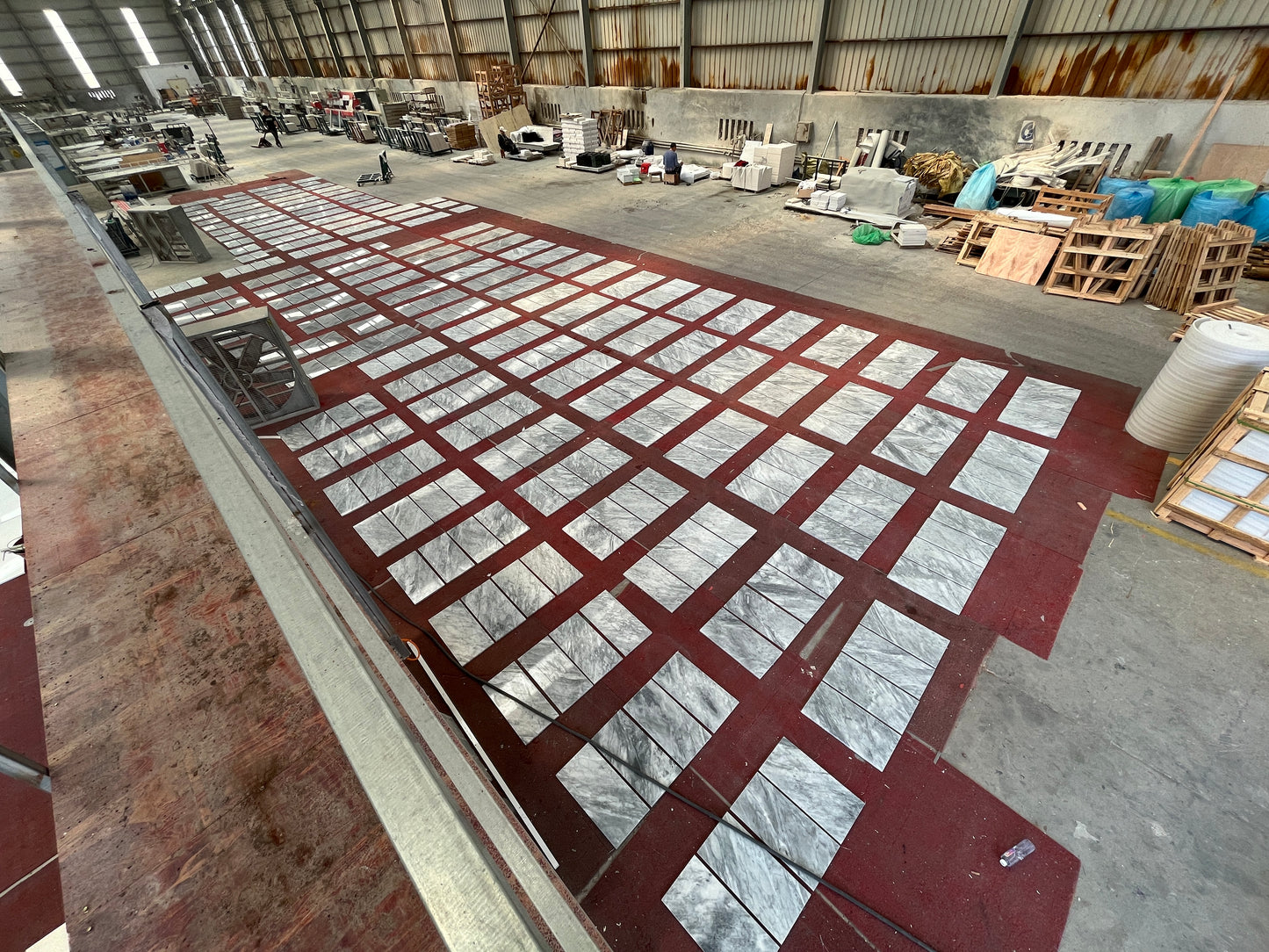 Marble tiles with unique gray veining laid out on a red surface in a warehouse