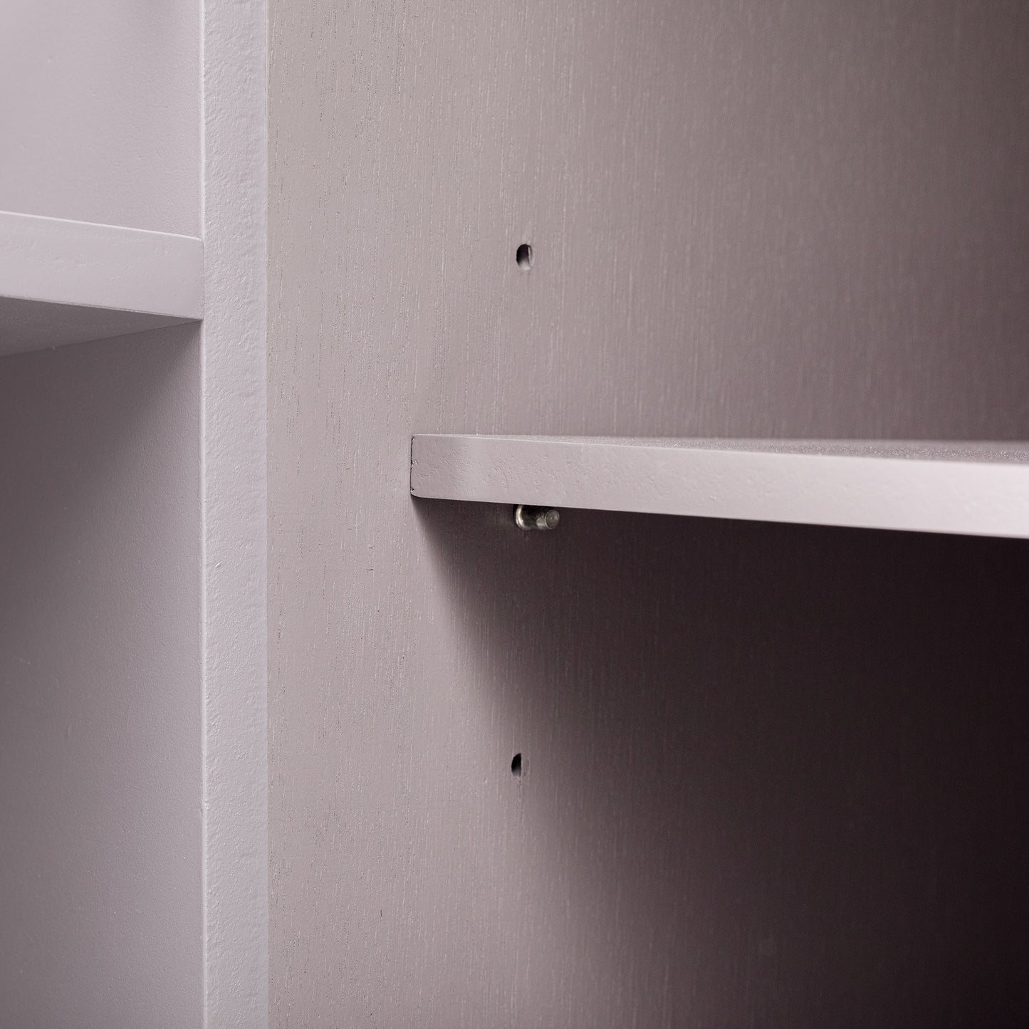 Closeup of a gray wooden shelf with visible wood grain detail and a clear shelf support pin
