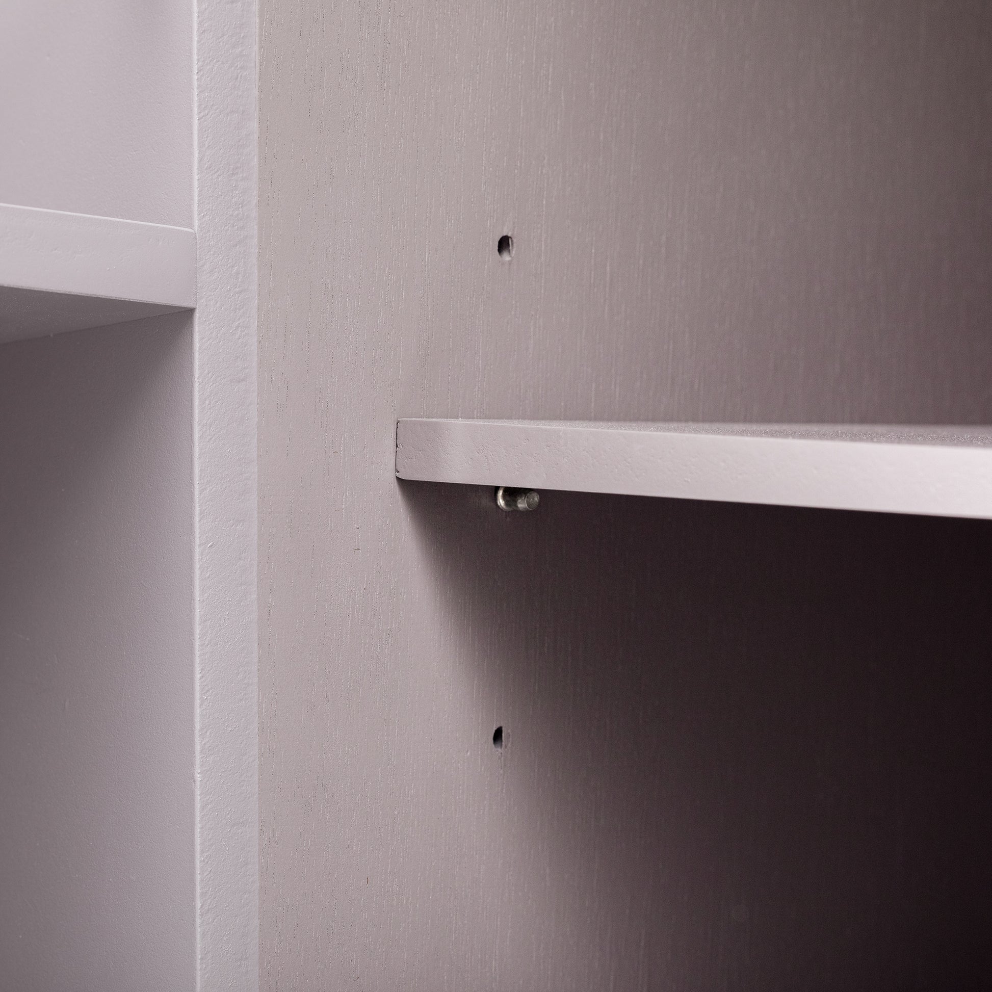 Closeup of a gray wooden shelf with visible wood grain detail and a clear shelf support pin