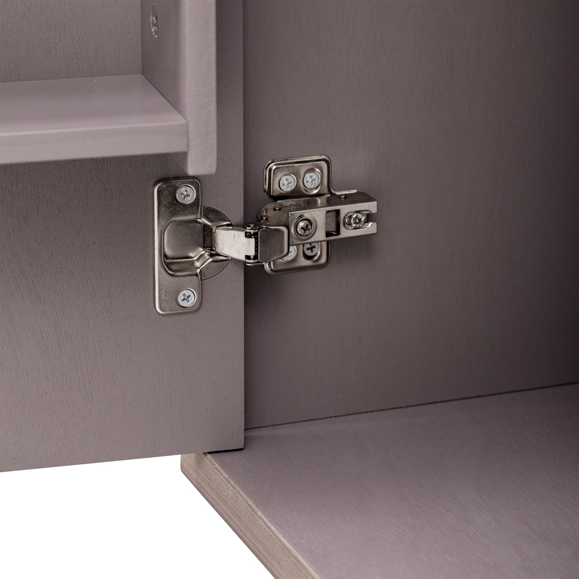 Closeup of a brushed nickel cabinet hinge on a taupe wood door