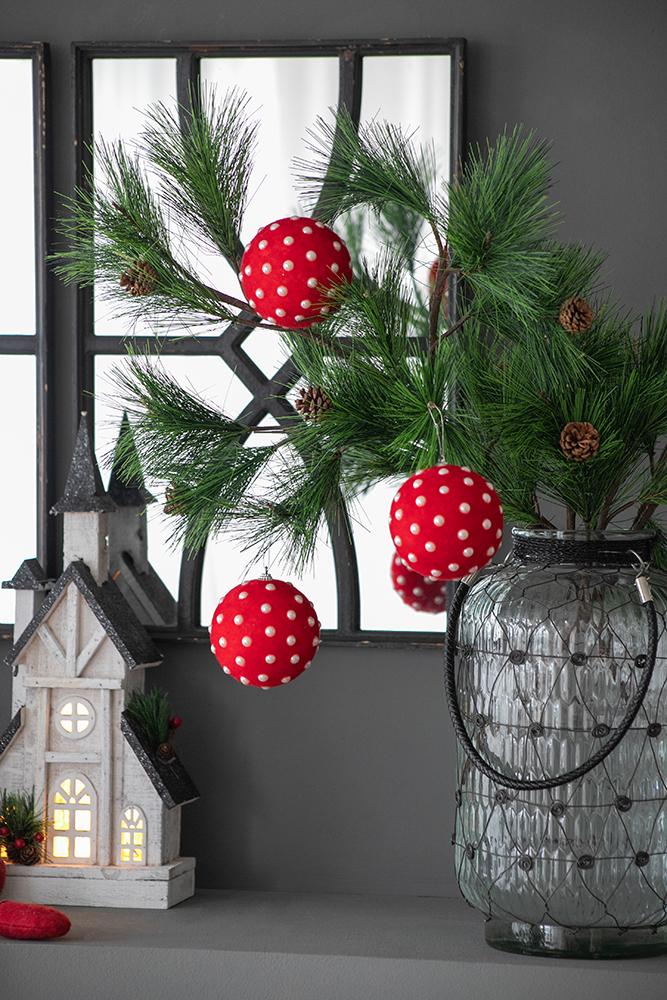 Red and white polka dot christmas ornament hanging from pine branches