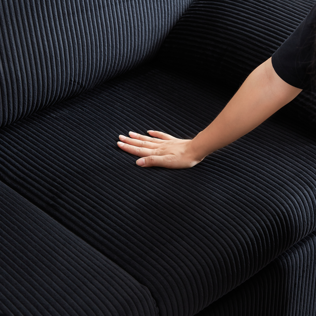 Black corduroy sofa texture with a hand gently pressing the plush fabric