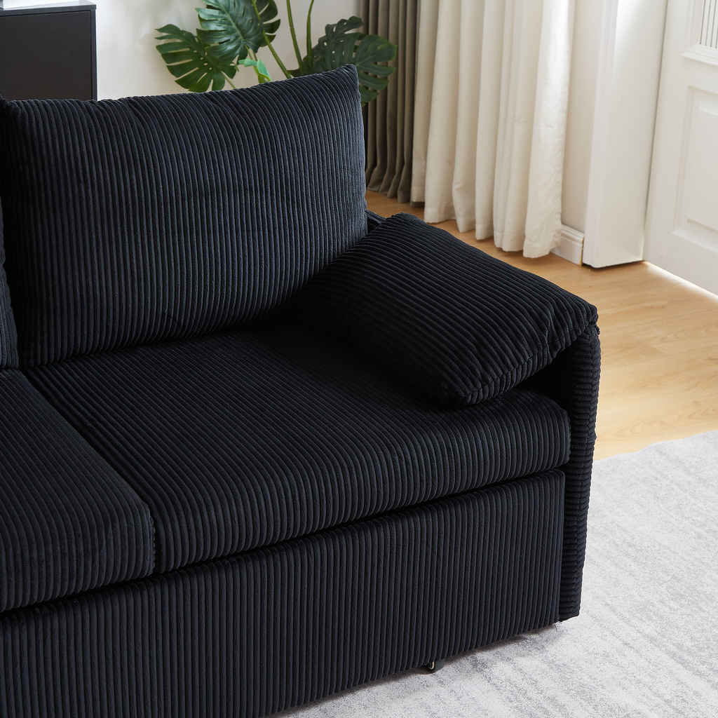 Closeup of a plush black corduroy sofa with deep channels and comfortable cushions