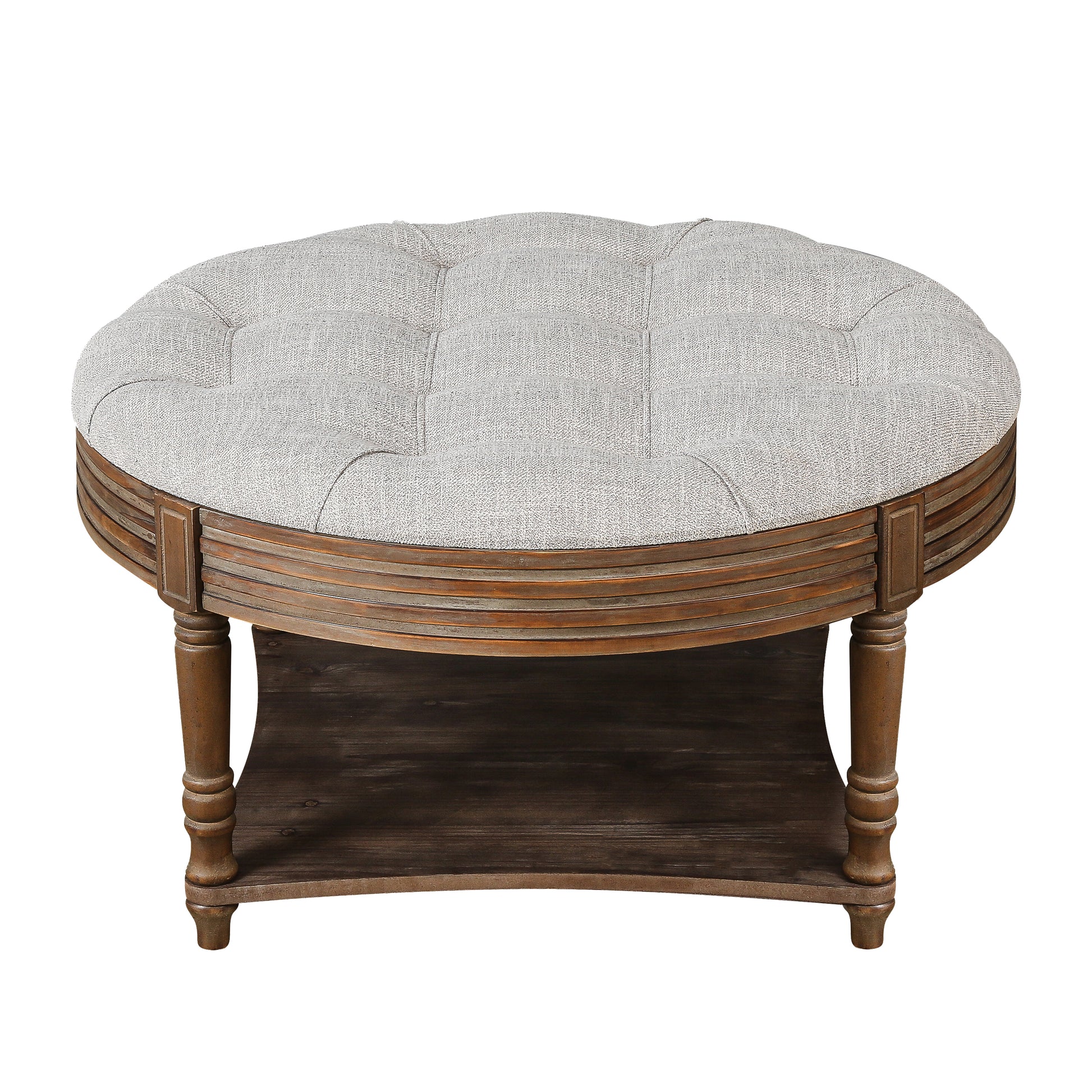 Tufted grey fabric ottoman with carved wooden base and lower shelf
