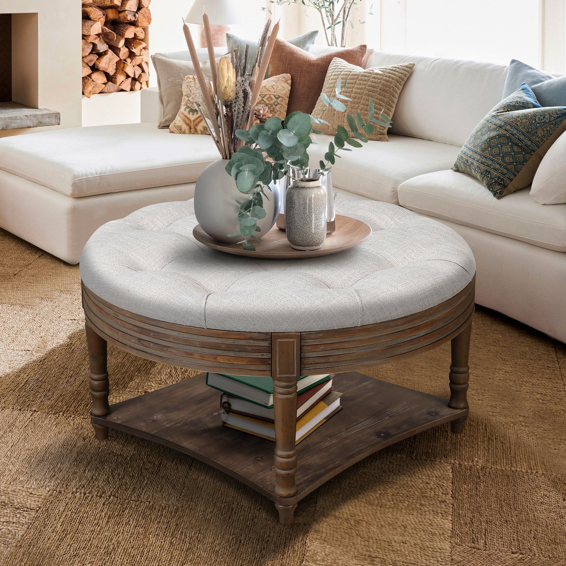 Tufted grey fabric round ottoman with wood base and lower shelf for books