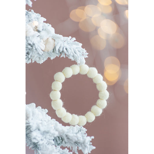 Cream felt ball garland hanging on a frosted tree branch festive holiday decor