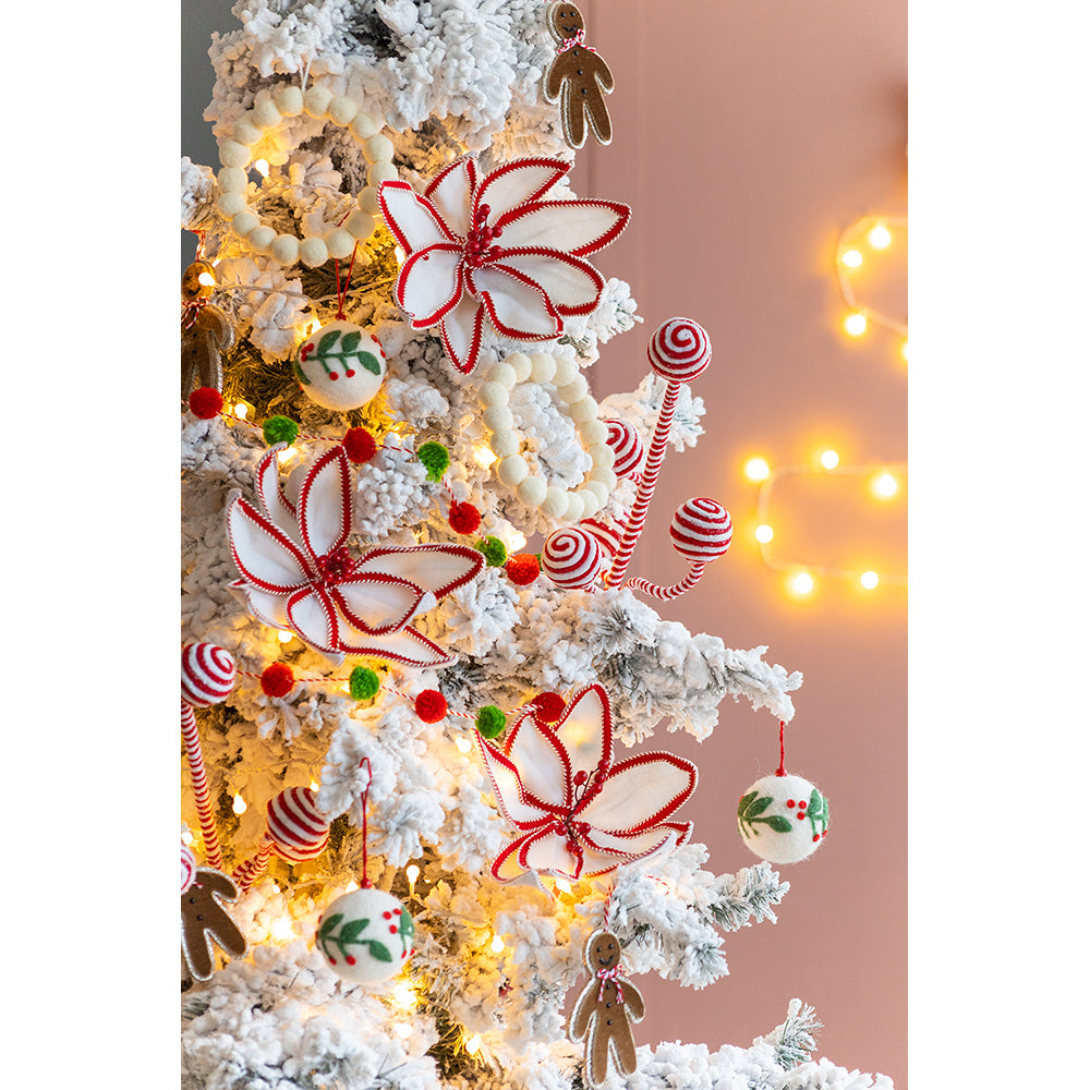 White and red fabric poinsettia ornaments with beaded centers on a flocked Christmas tree
