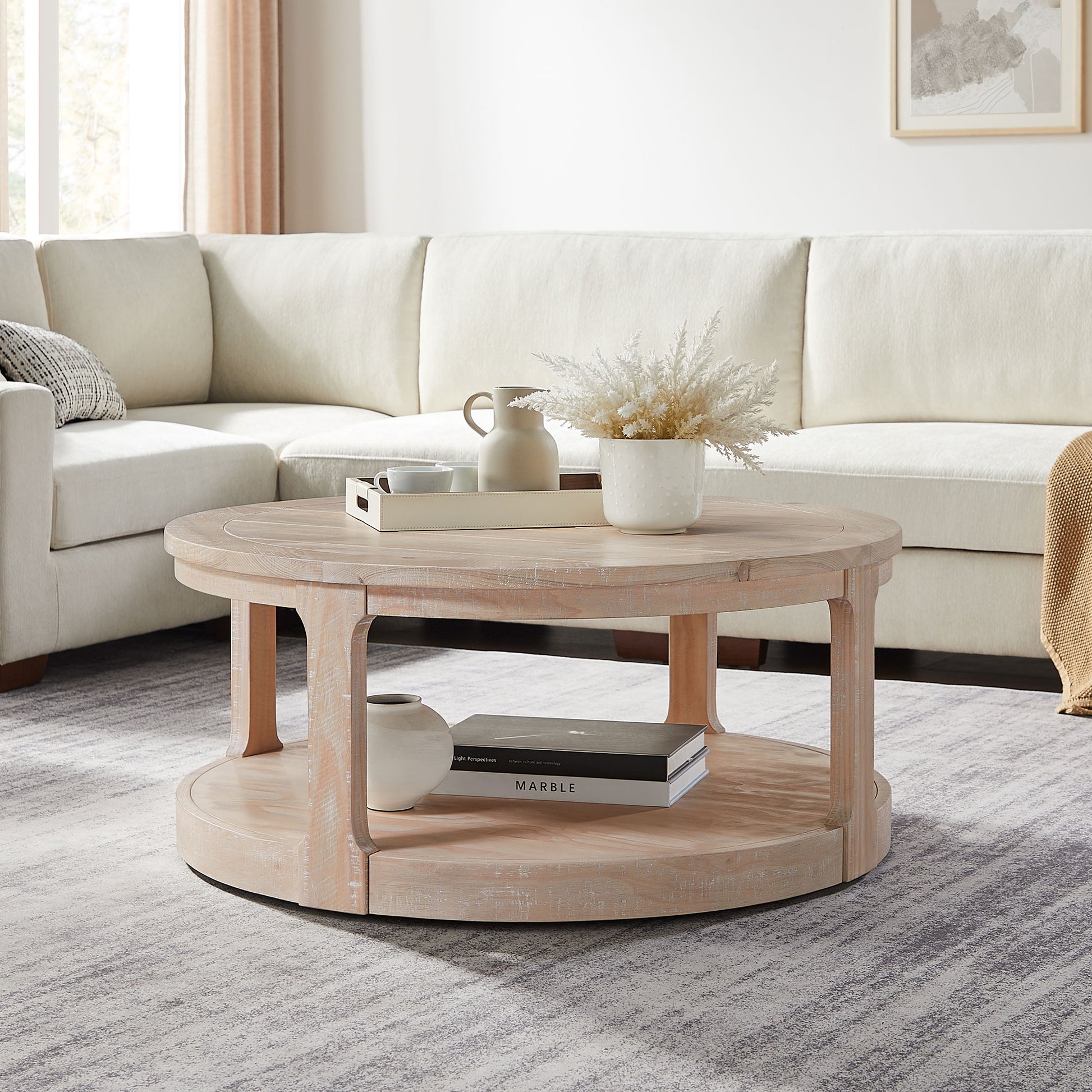Round distressed wood coffee table with lower shelf and decorative items