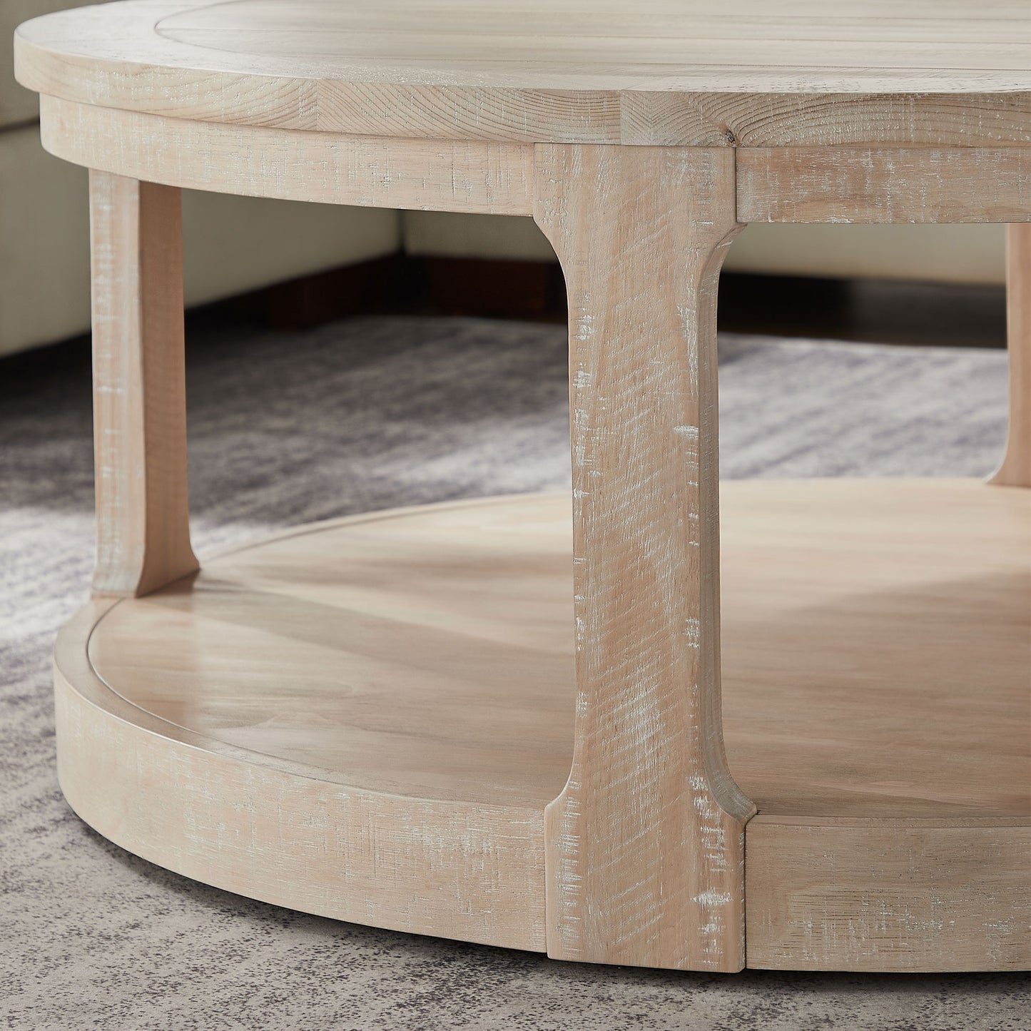 Round whitewashed wood coffee table with a lower shelf and carved legs