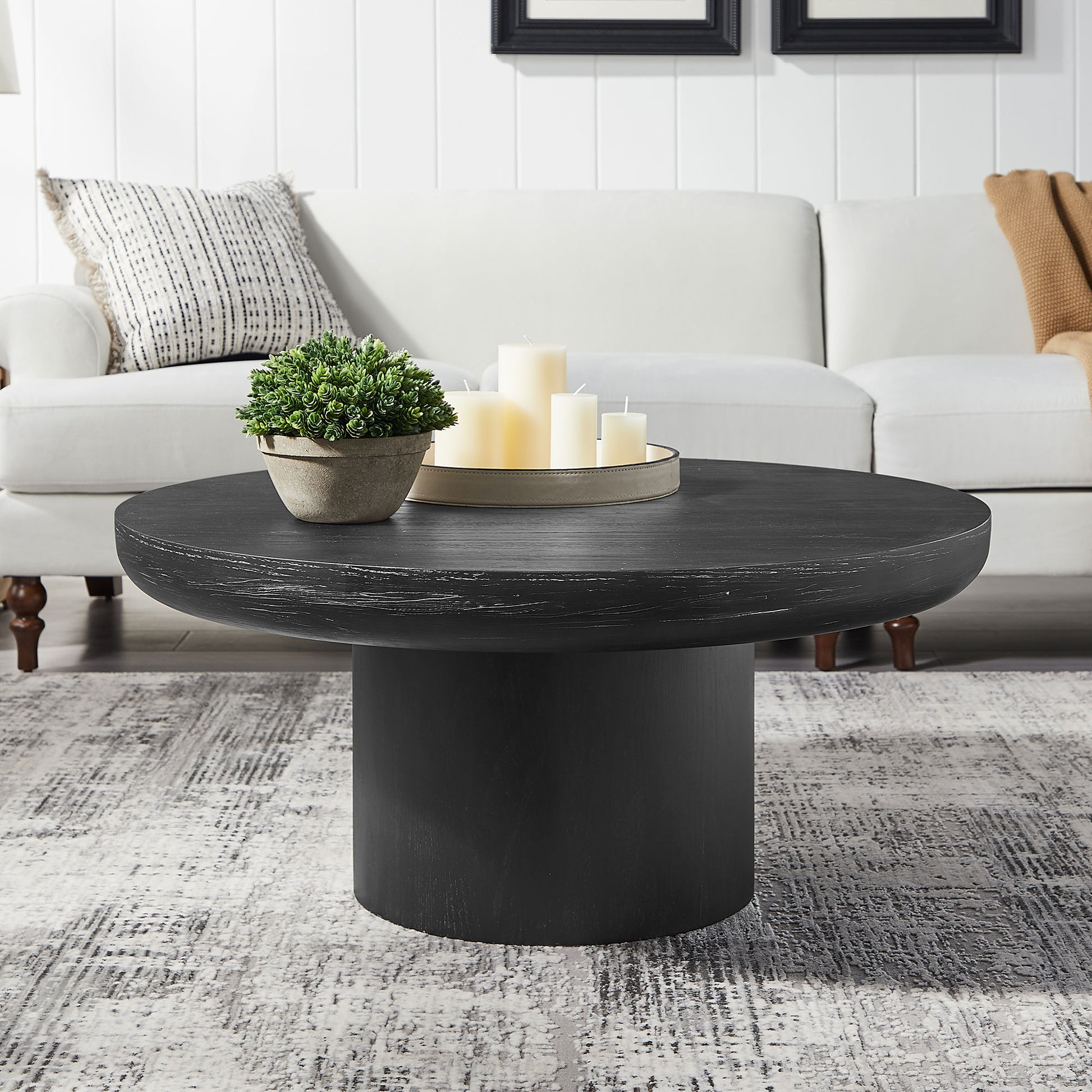 Black round wood coffee table with a distressed finish and cylindrical base