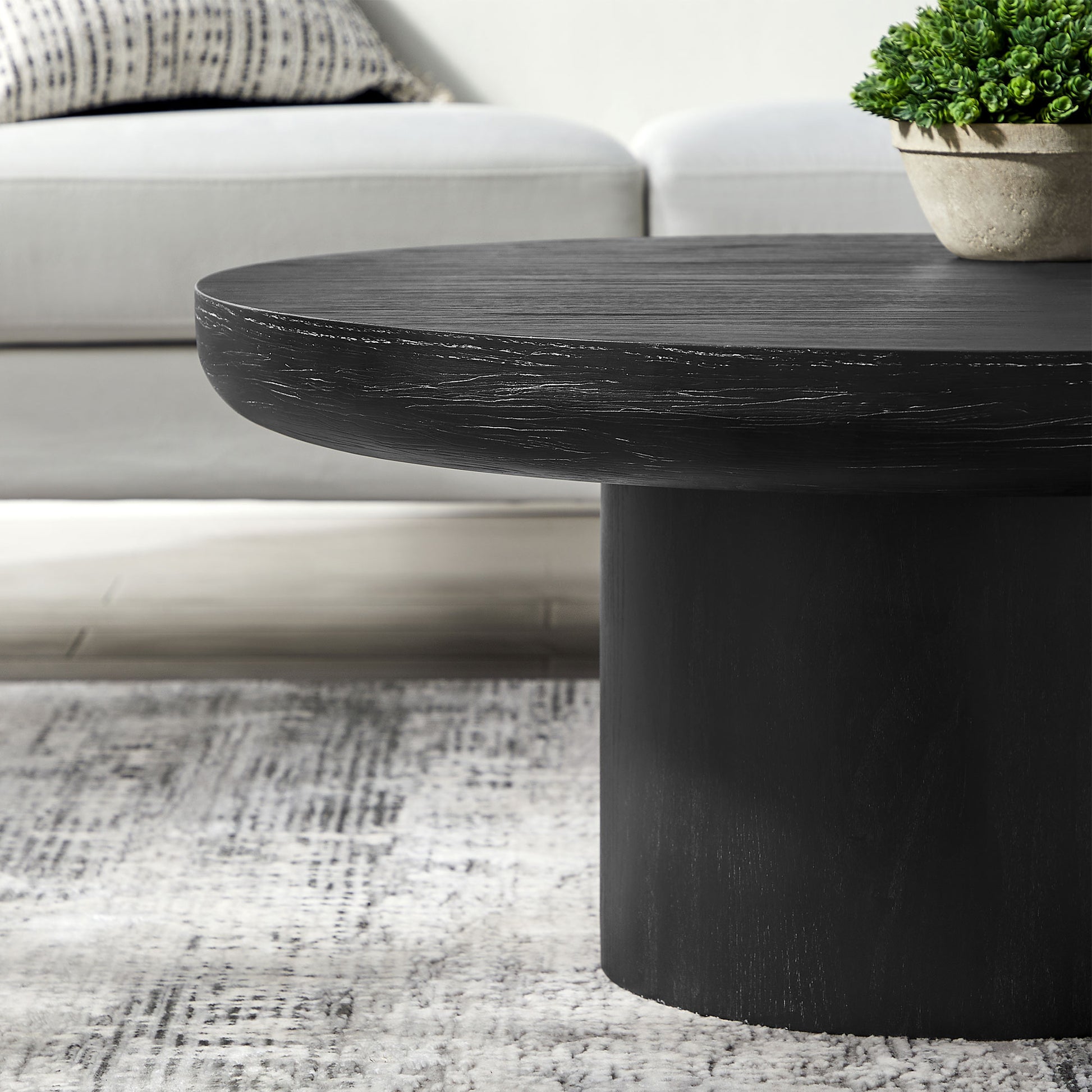 Black round wooden coffee table with distressed finish and cylindrical base