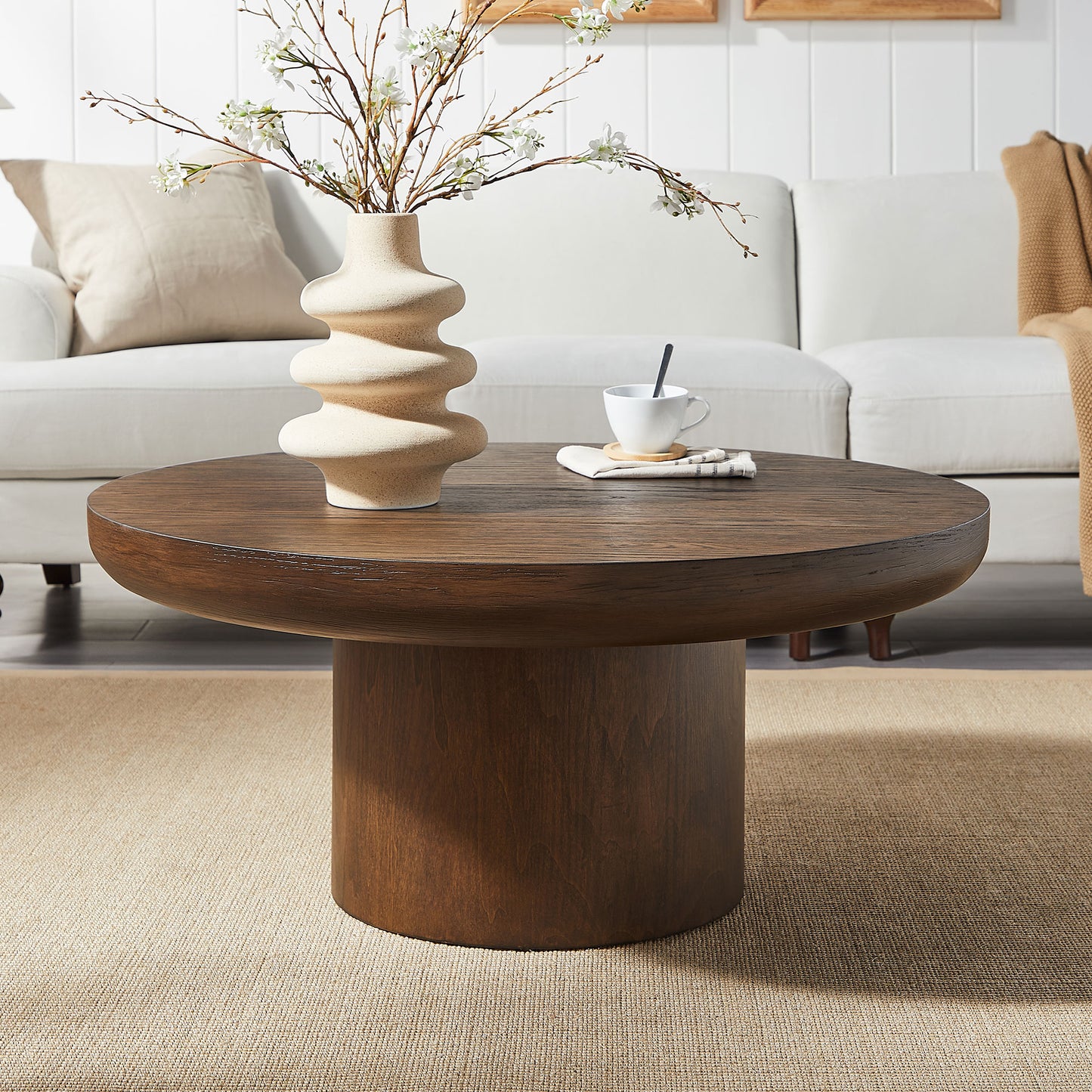 Round dark wood coffee table with a cylindrical pedestal base perfect for living room settings