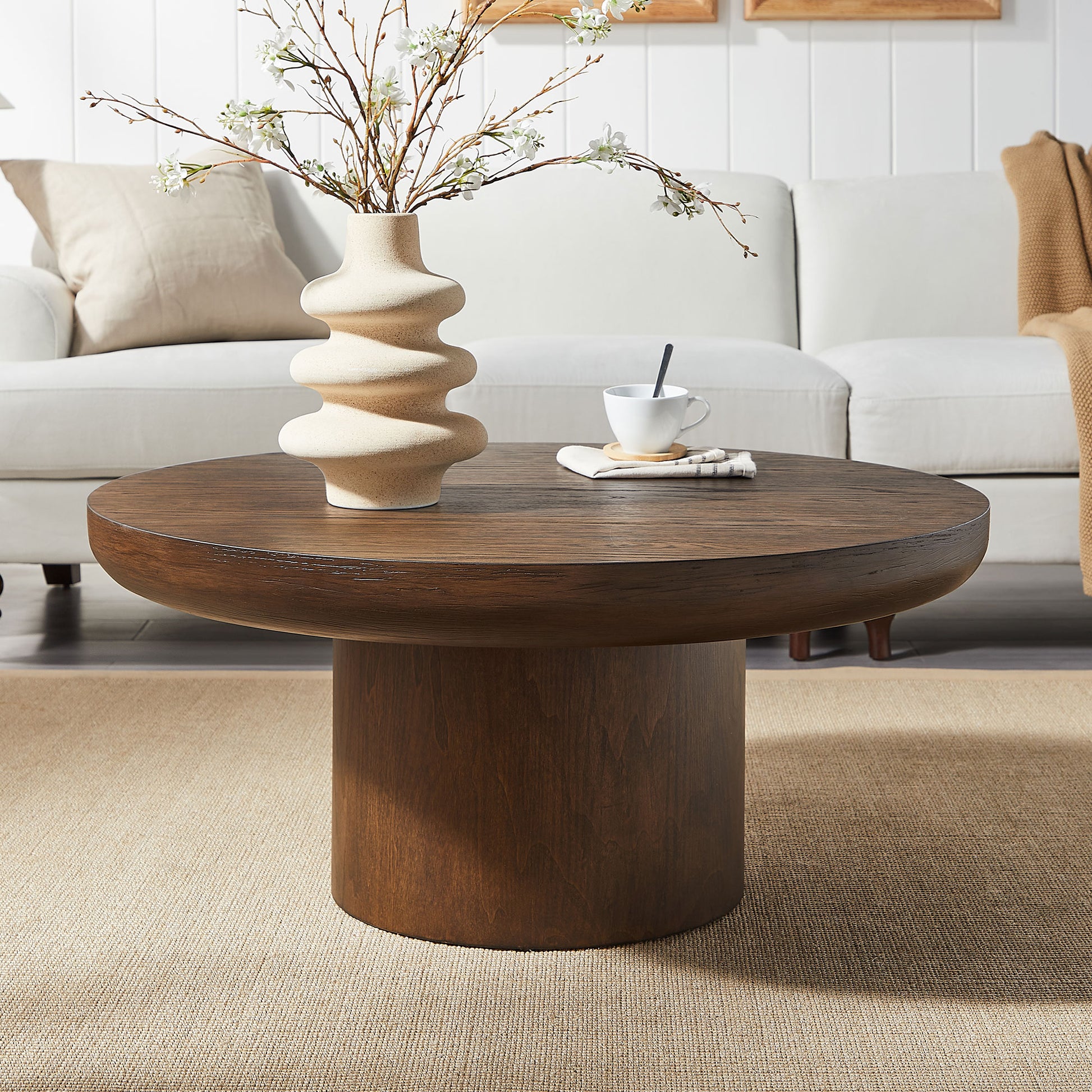 Round dark wood coffee table with a cylindrical pedestal base perfect for living room settings