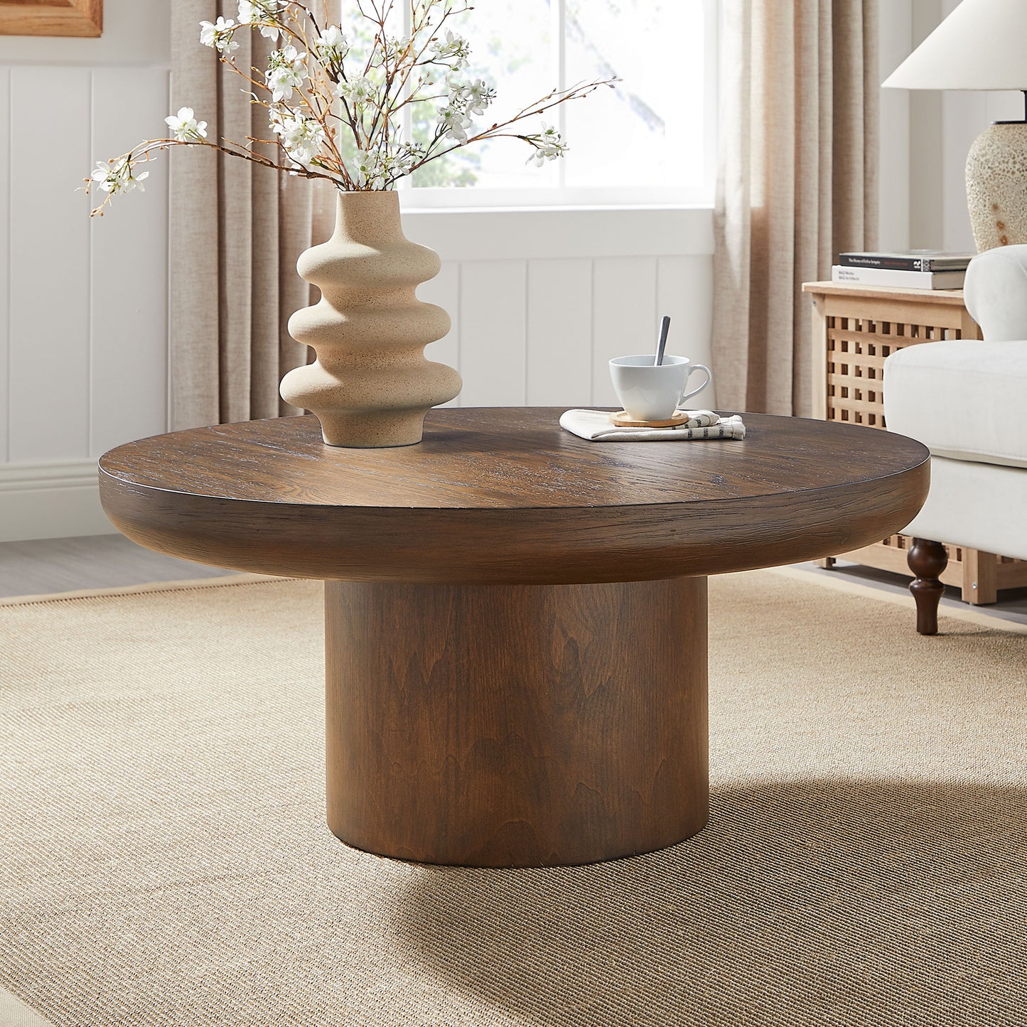 Round dark wood coffee table with a cylindrical pedestal base perfect for modern living rooms