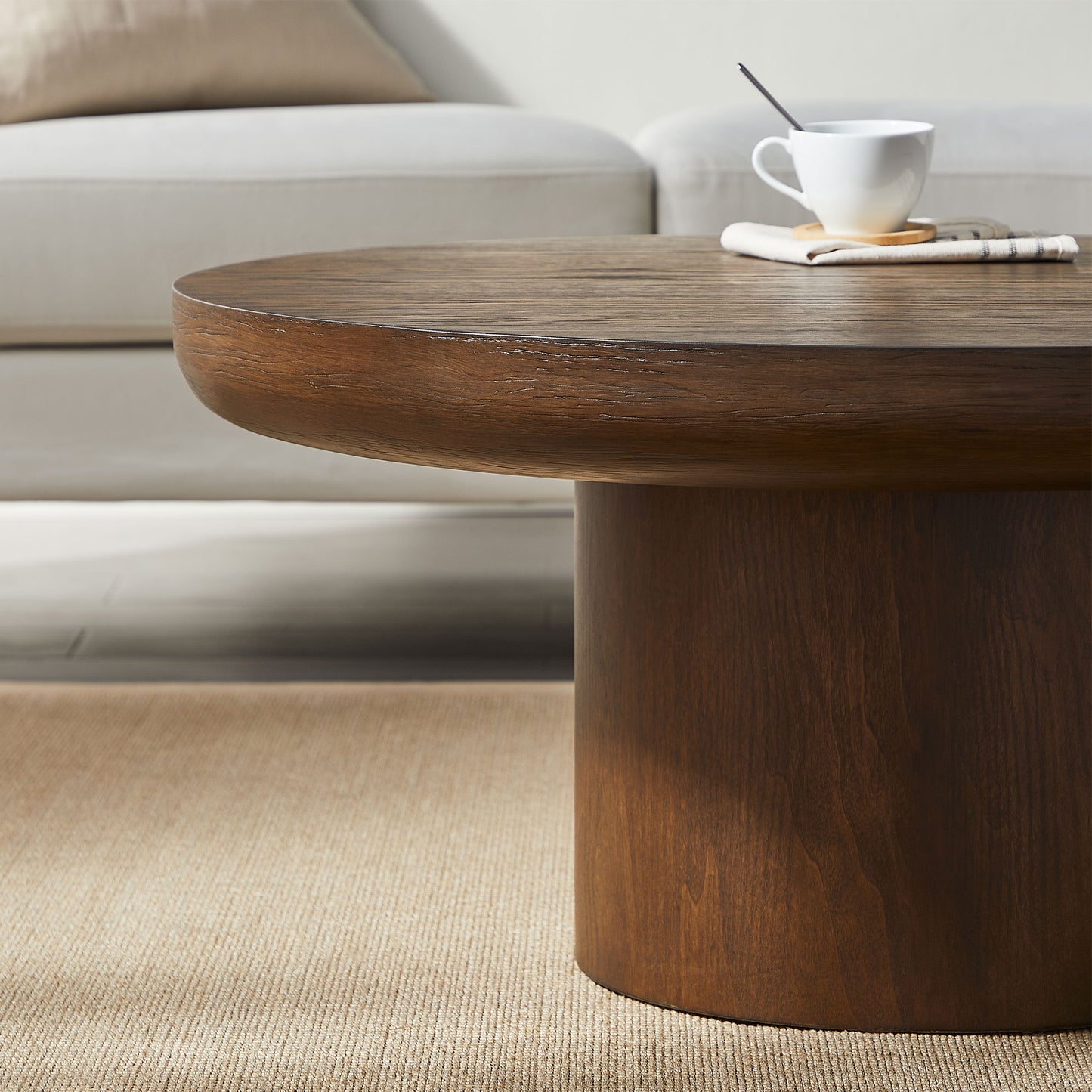 Round dark wood coffee table with a thick smooth surface and cylindrical base