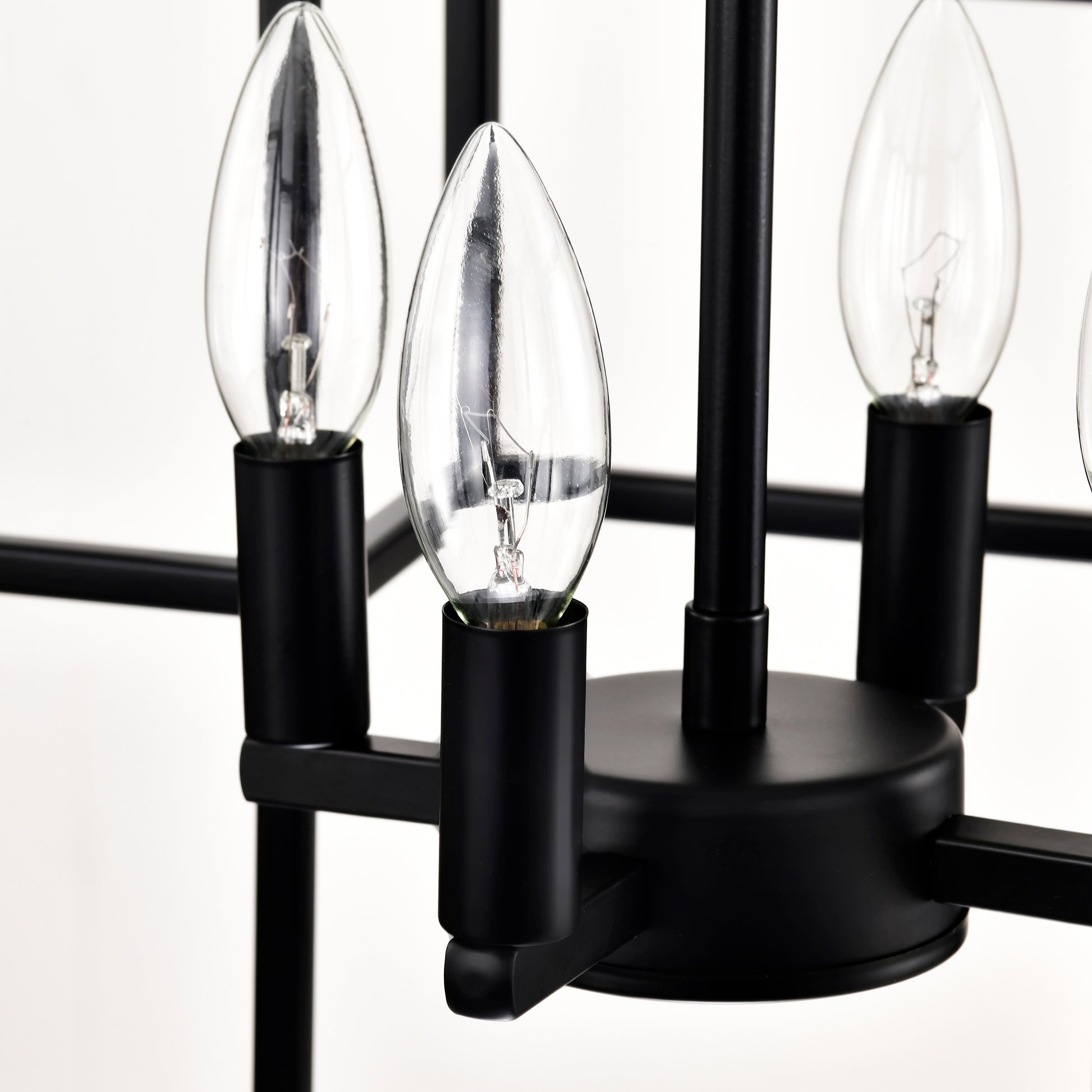Closeup of a black metal chandelier arm holding a clear candelabra bulb