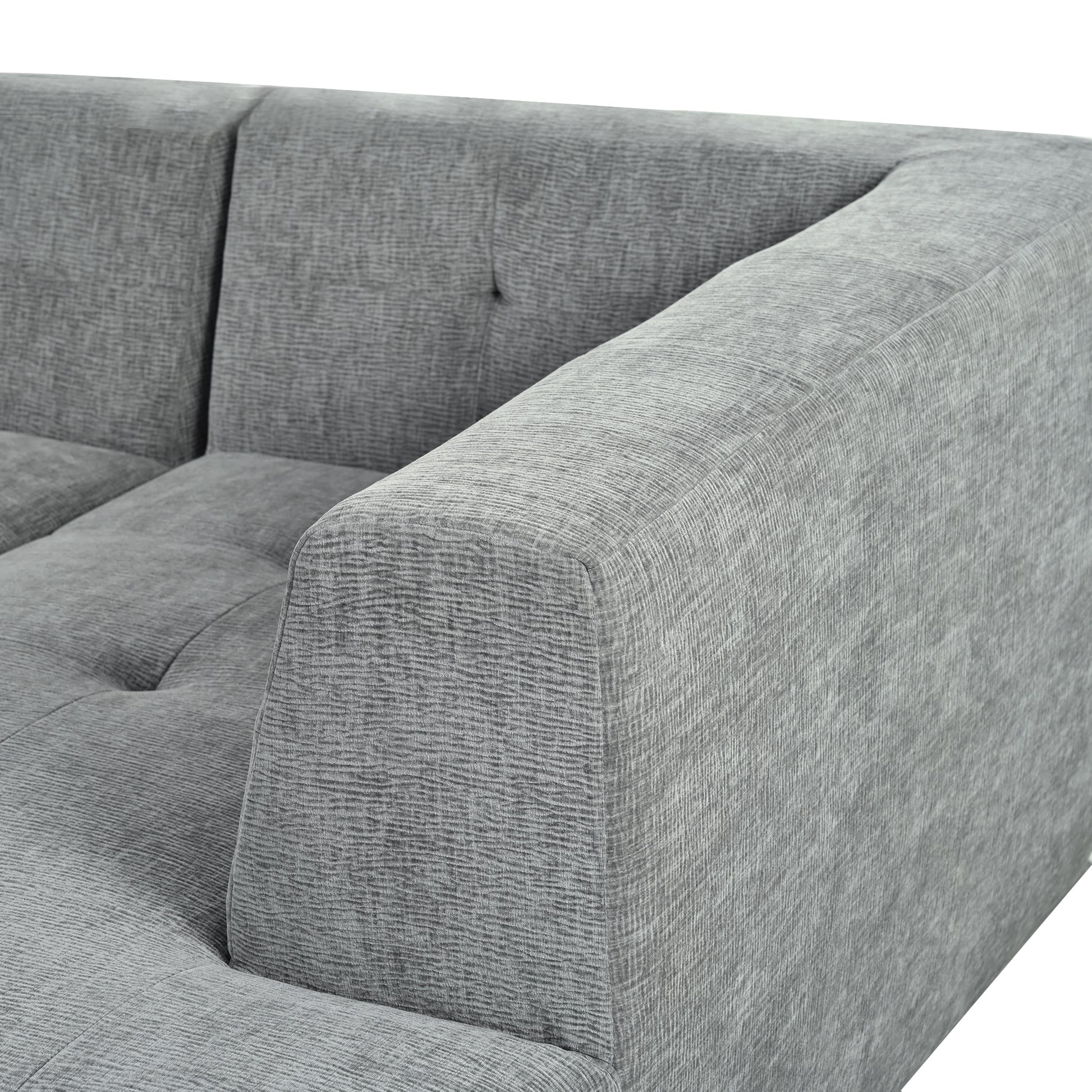 Closeup of a grey textured fabric sofa armrest and tufted seat cushion