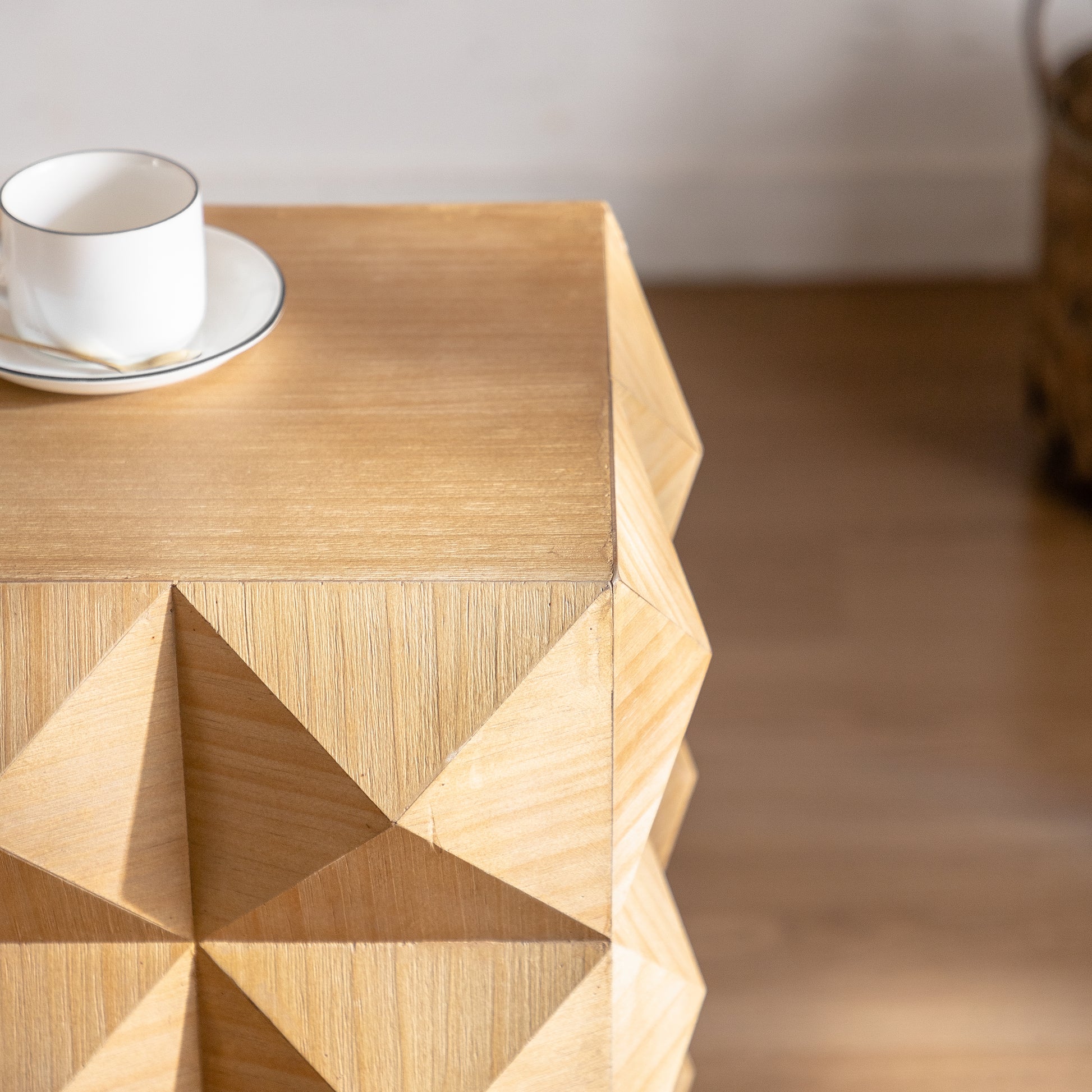 Geometric carved wood accent table with a light natural finish perfect for small spaces
