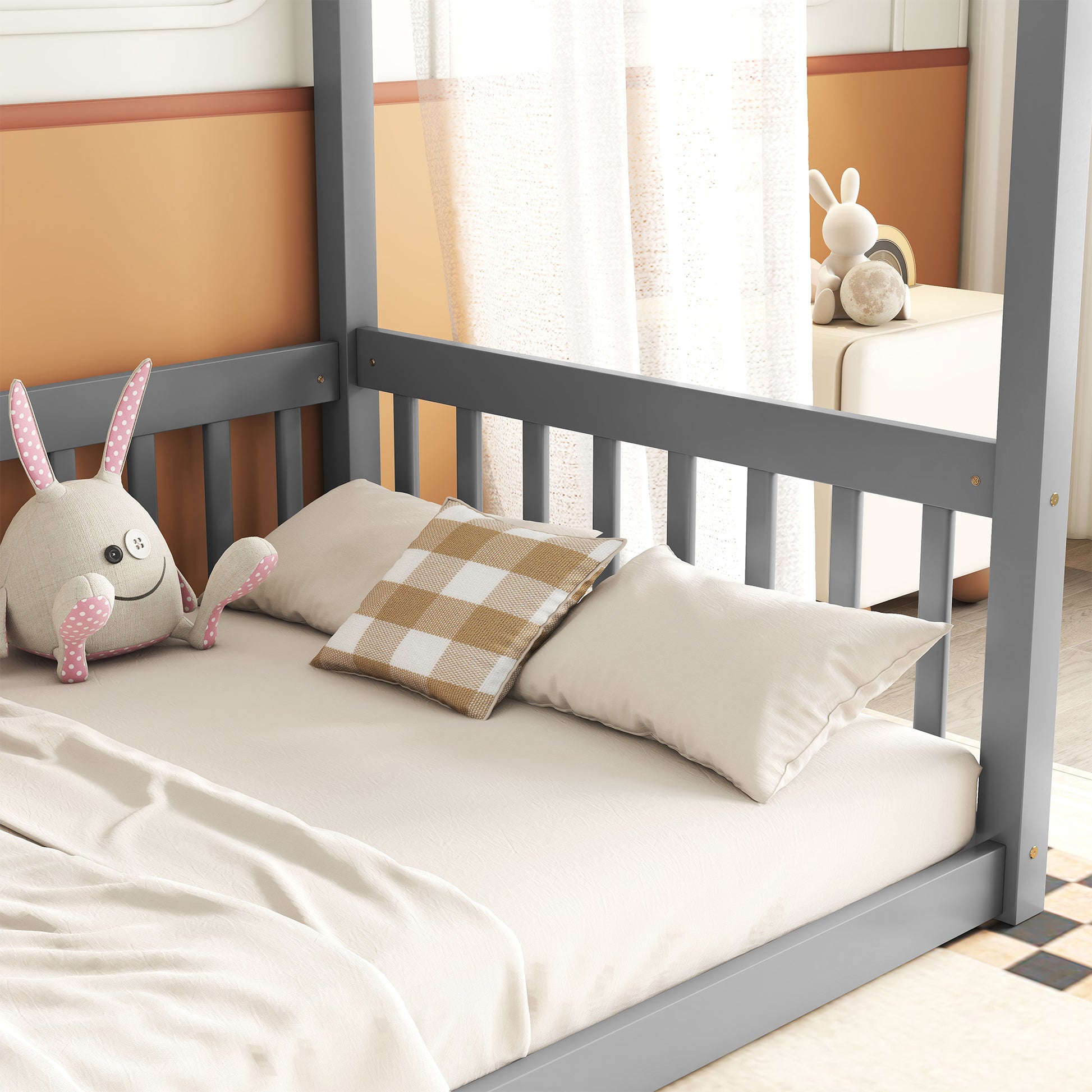 Gray canopy bed frame with plush bedding and stuffed bunny toy