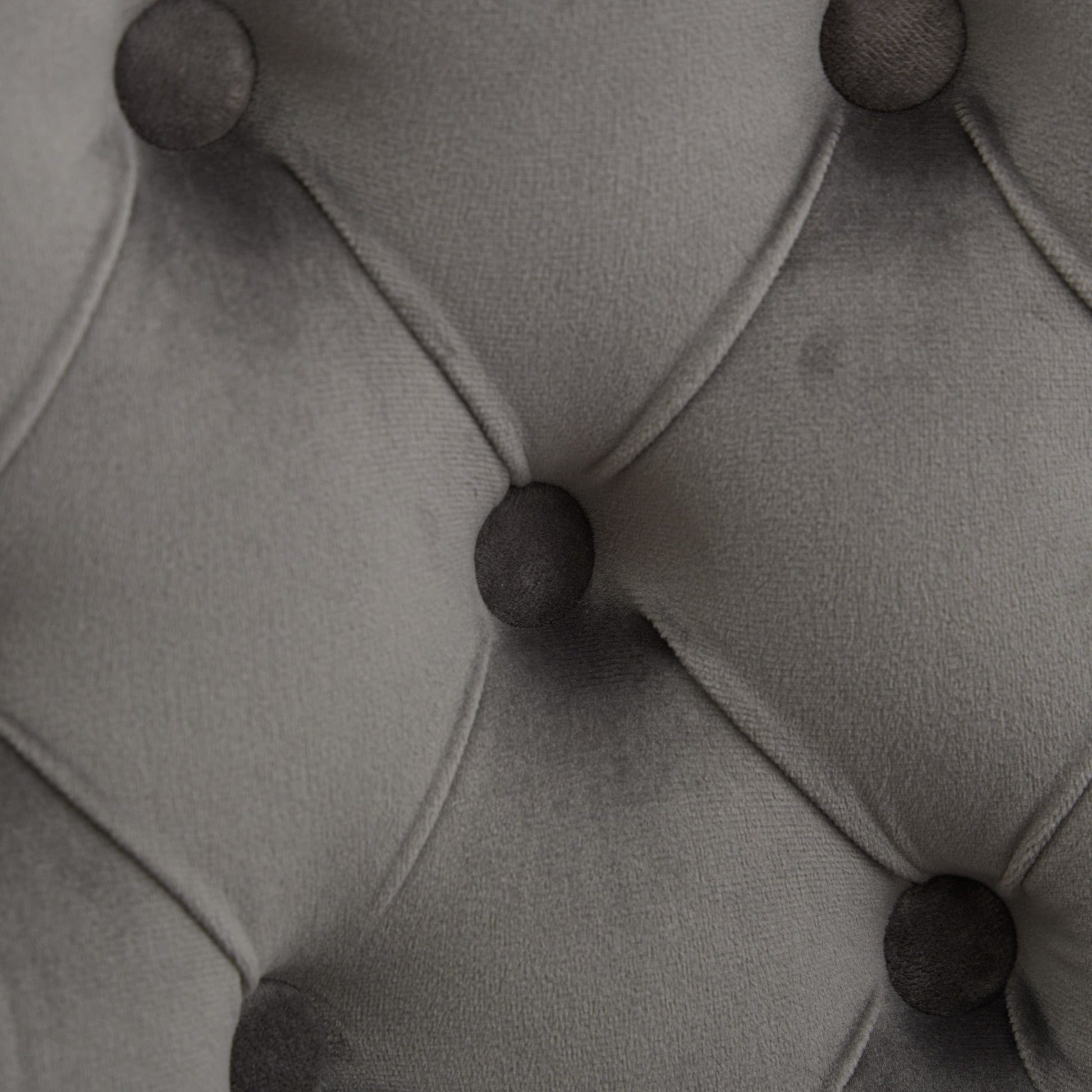 Closeup of gray velvet fabric with deep button tufting detail for upholstery