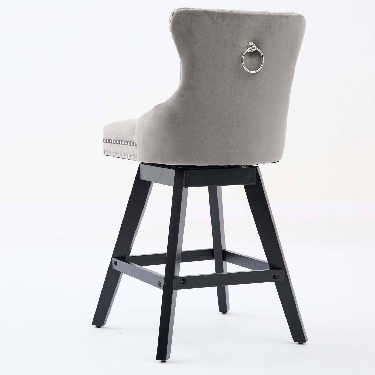 Gray velvet tufted bar stool with silver ring pull on back and dark wood legs