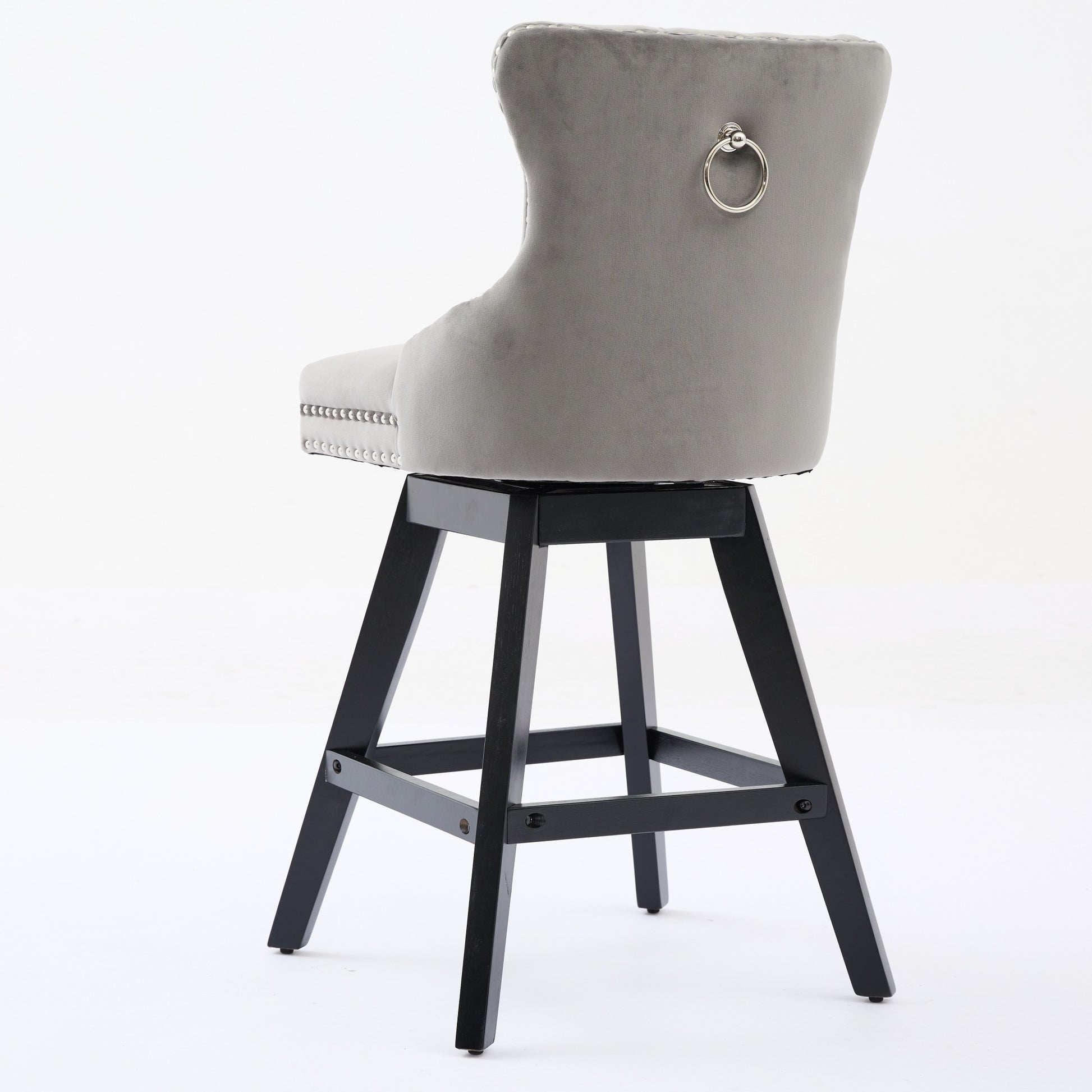 Gray velvet tufted bar stool with silver ring pull on back and dark wood legs