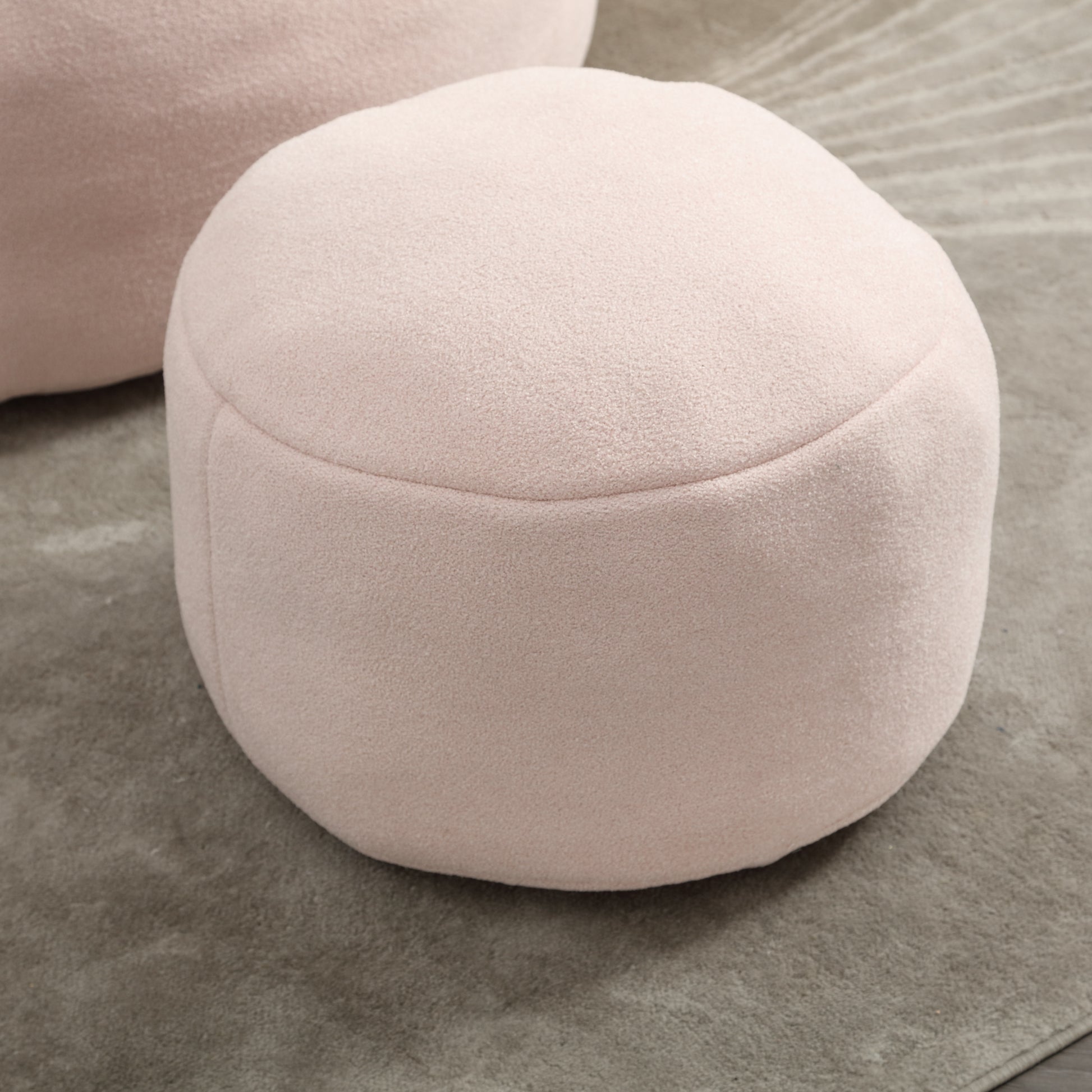 Round blush pink fabric ottoman with subtle textured surface