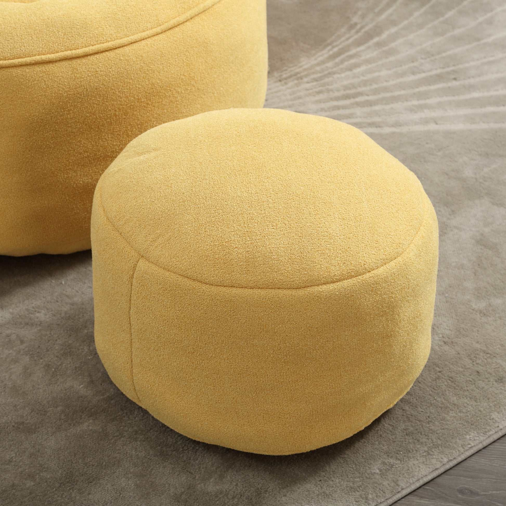 Round mustard yellow fabric ottoman perfect as a footrest or extra seating in a modern living room