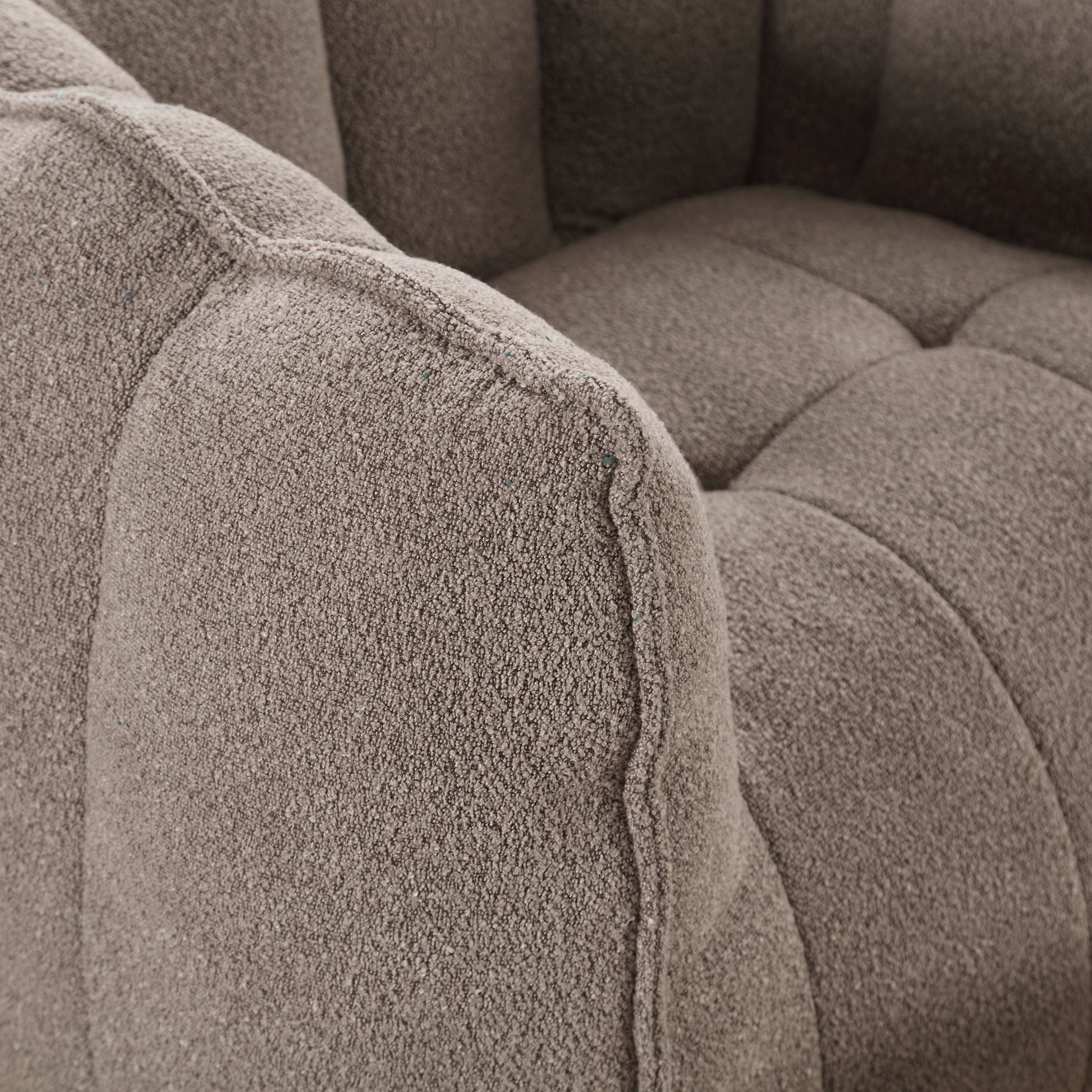 Closeup of textured boucle fabric armchair in taupe with channel tufting detail